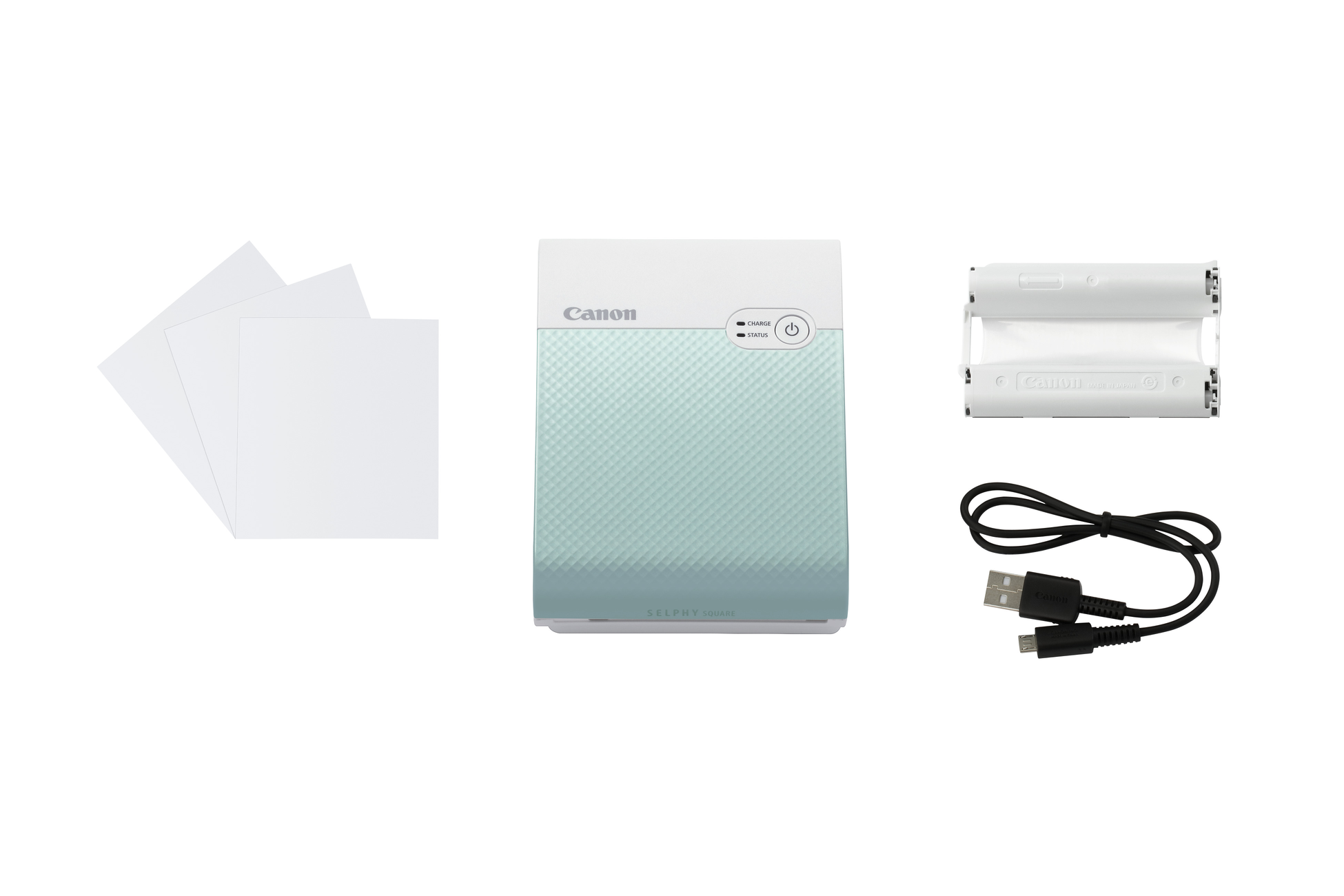 Canon Selphy printer and accessories. Includes printer, paper, battery pack, and USB cable. White background.