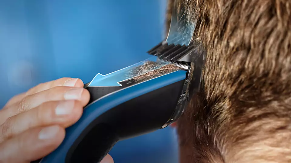 Une personne utilise une tondeuse à cheveux, gros plan.