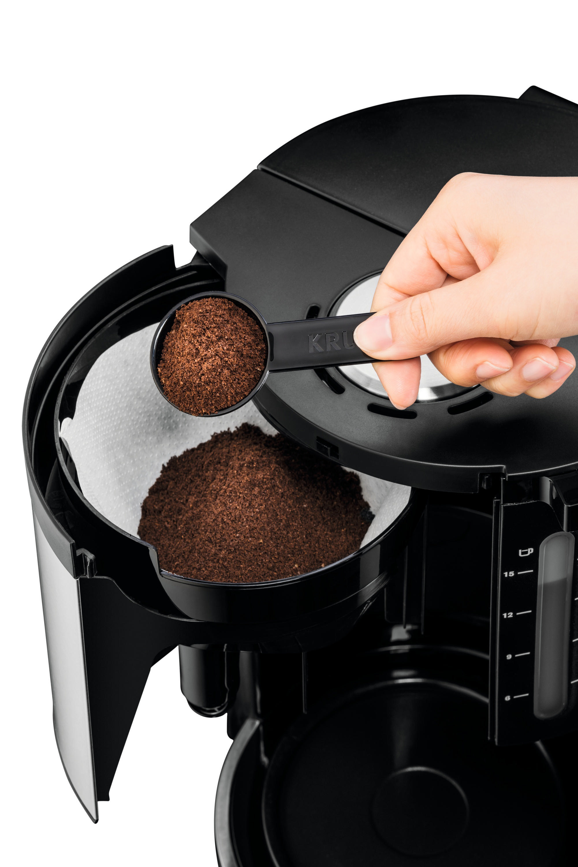 Eine Person, die Kaffeepulver in einen Filter einer schwarzen Krups Kaffeemaschine gibt.