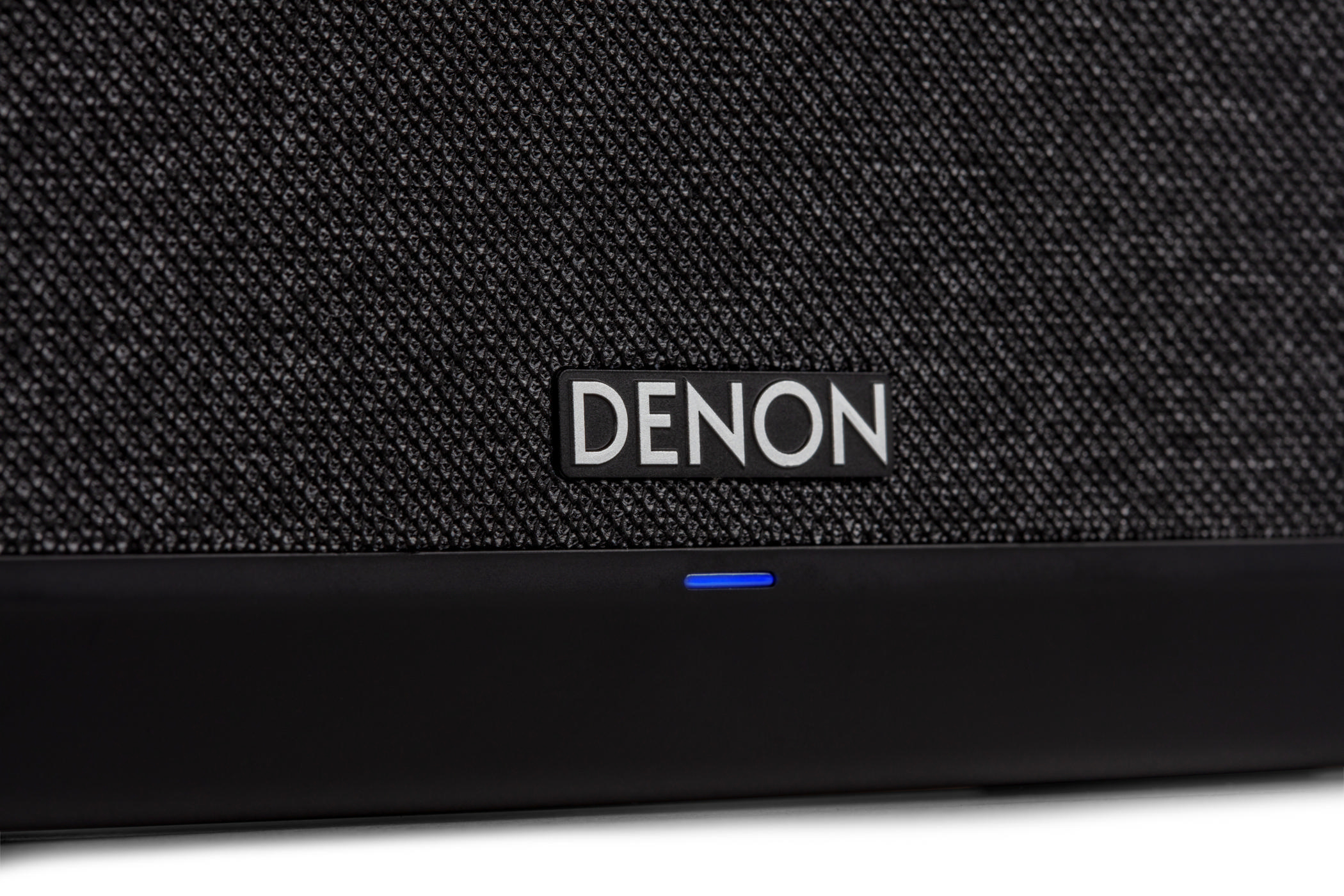 Denon-Lautsprecher, Nahaufnahme des Logos und einer blauen Betriebsanzeige.