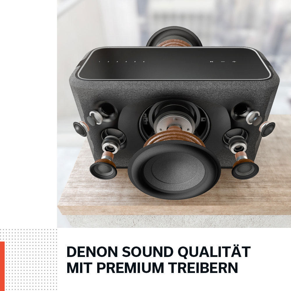 Ein schwarzes Denon-Soundsystem mit Lautsprechern auf einem Holztisch mit Text darunter.