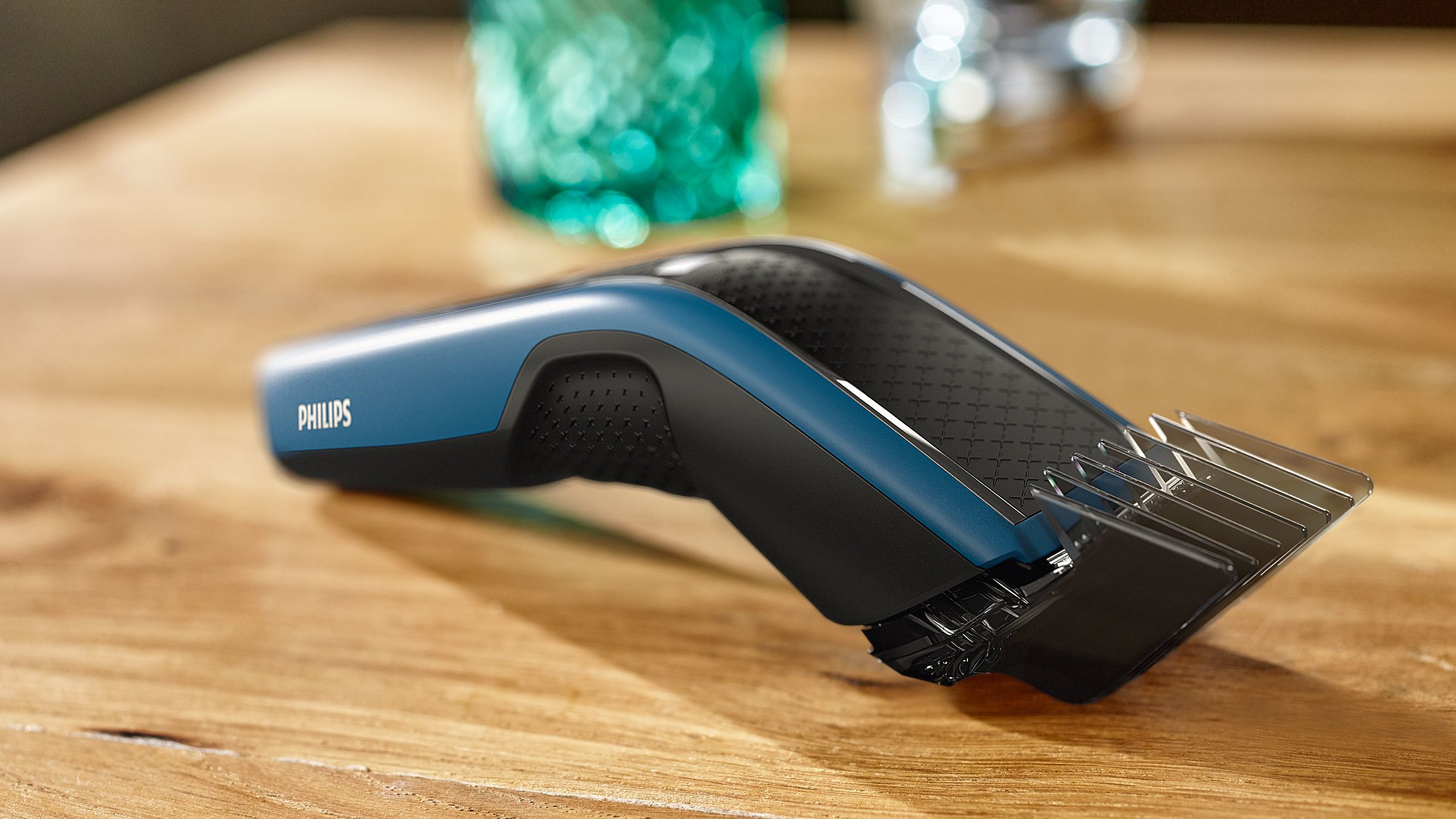 Une tondeuse à cheveux Philips noire et bleue est sur une table en bois, avec un arrière-plan flou.