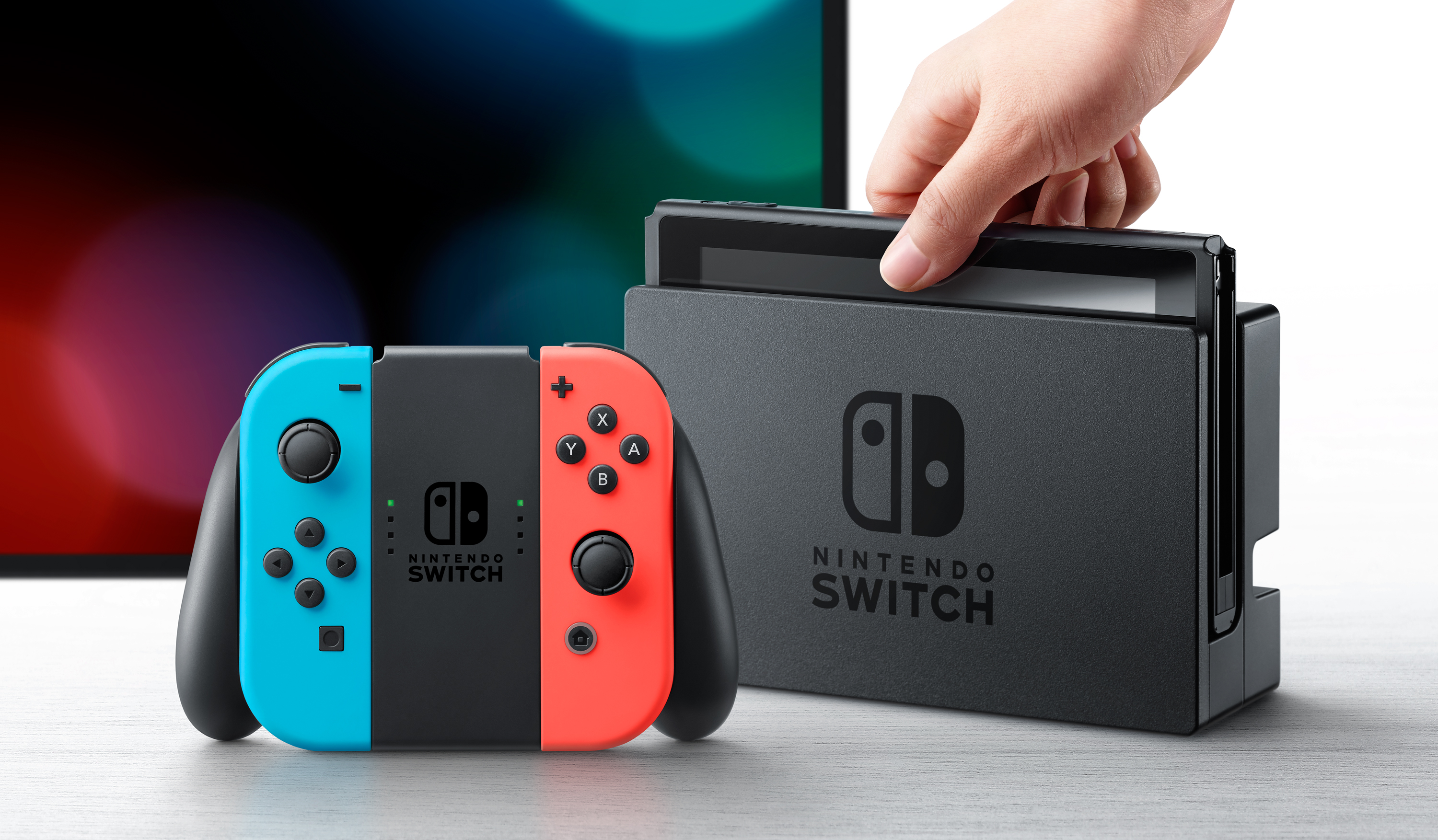 Bir Nintendo Switch konsolu, Joy-Con kontrolcüler ve bir yuva masada.