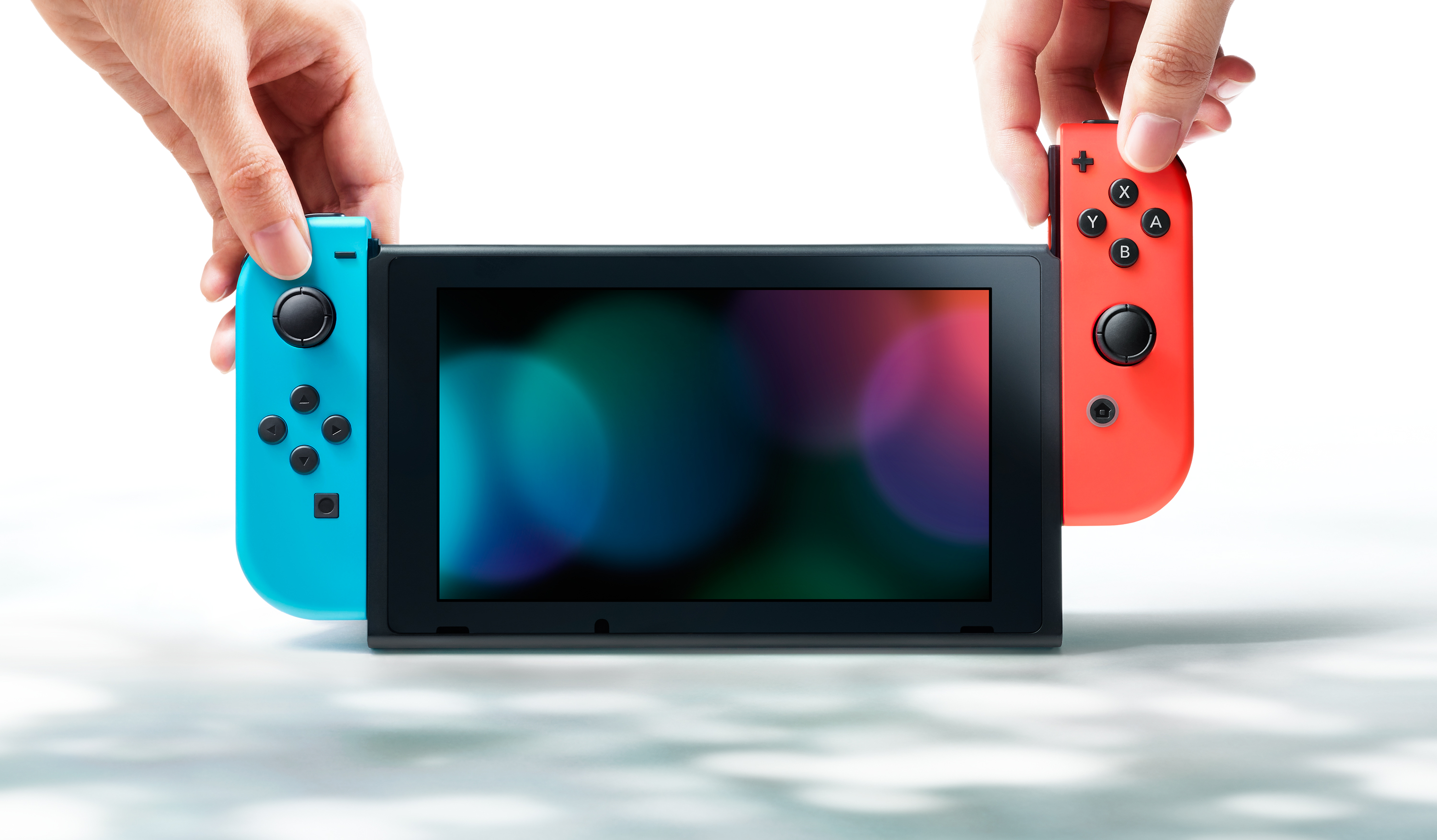 Eller bir Nintendo Switch konsolu tutuyor. Joy-Con kontrolcüleri her iki tarafa takılı.