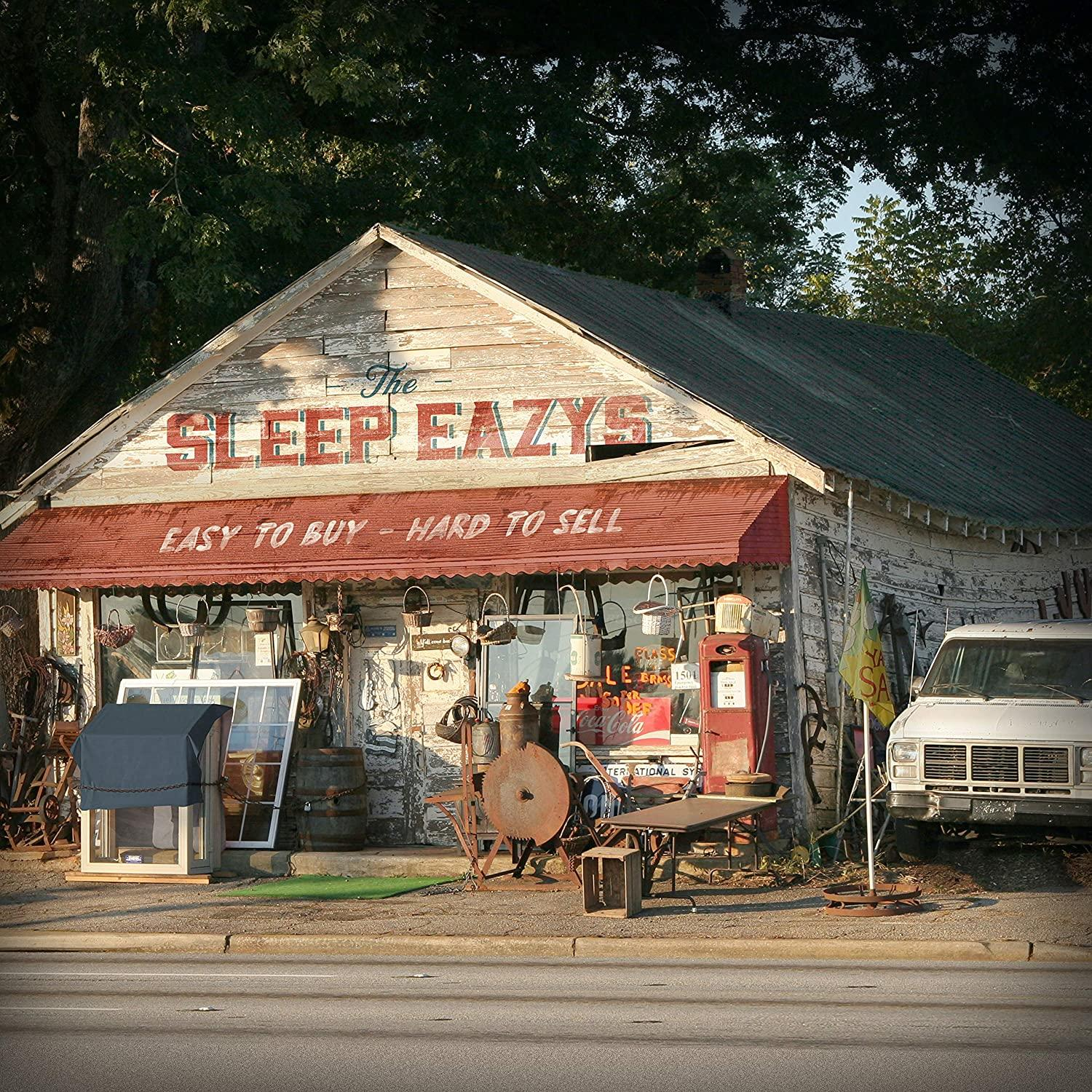 Altes Gebäude mit roter Markise. Schild 'The Sleep Eazys'. Weißer Transporter geparkt.
