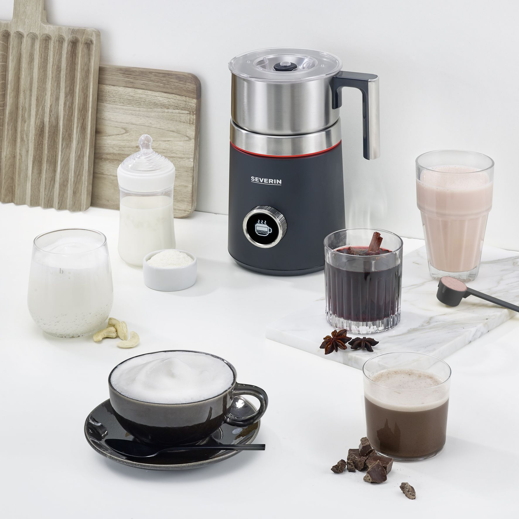 Eine Kaffeeszene mit Milchaufschäumer, verschiedenen Getränken, einer Tasse Kaffee und Zutaten auf weißer Oberfläche.