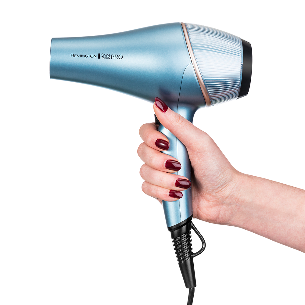Een hand van een vrouw die een lichtblauwe Remington haardroger vasthoudt. De droger is ook goud en zwart.