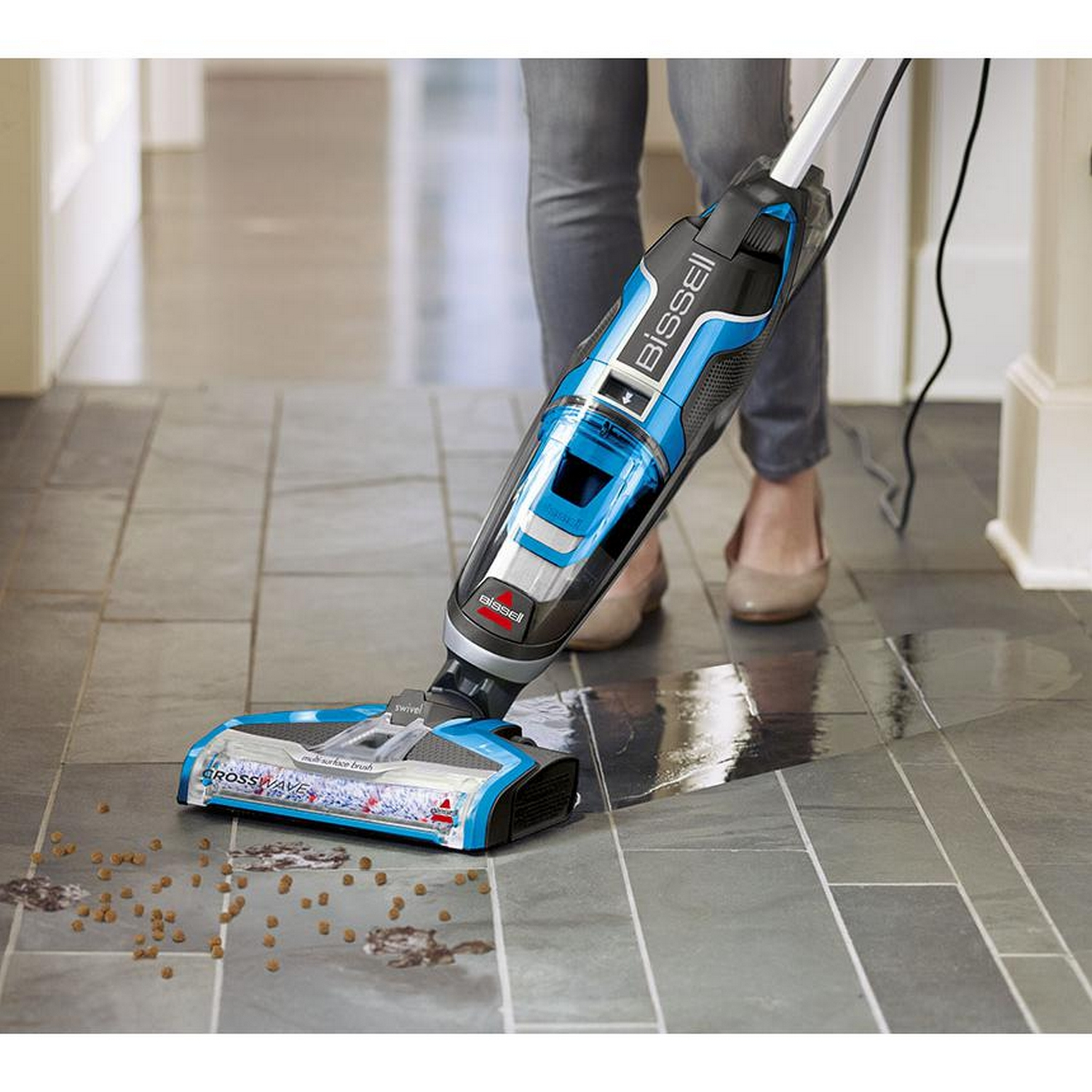 Bissell CrossWave aspirando un suelo embaldosado, líquido de limpieza y residuos visibles.