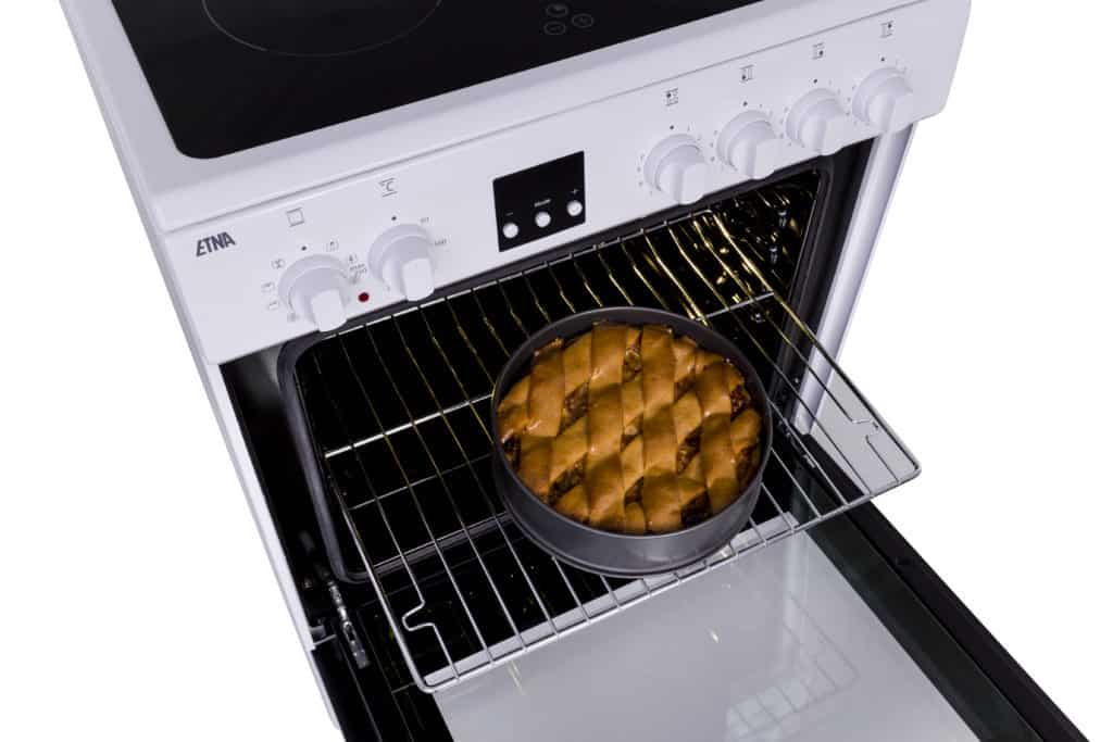 Een oven met een taart erin, open zodat de kijker het interieur kan zien.