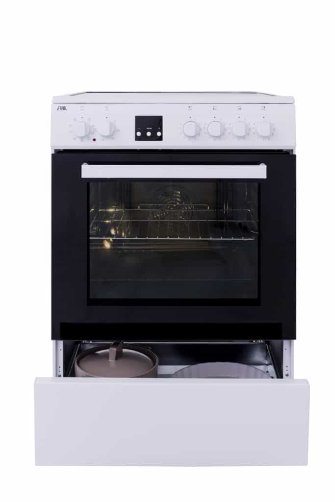 Witte oven met zwarte ovendeur. Lade onder de oven is open, onthult een pot.