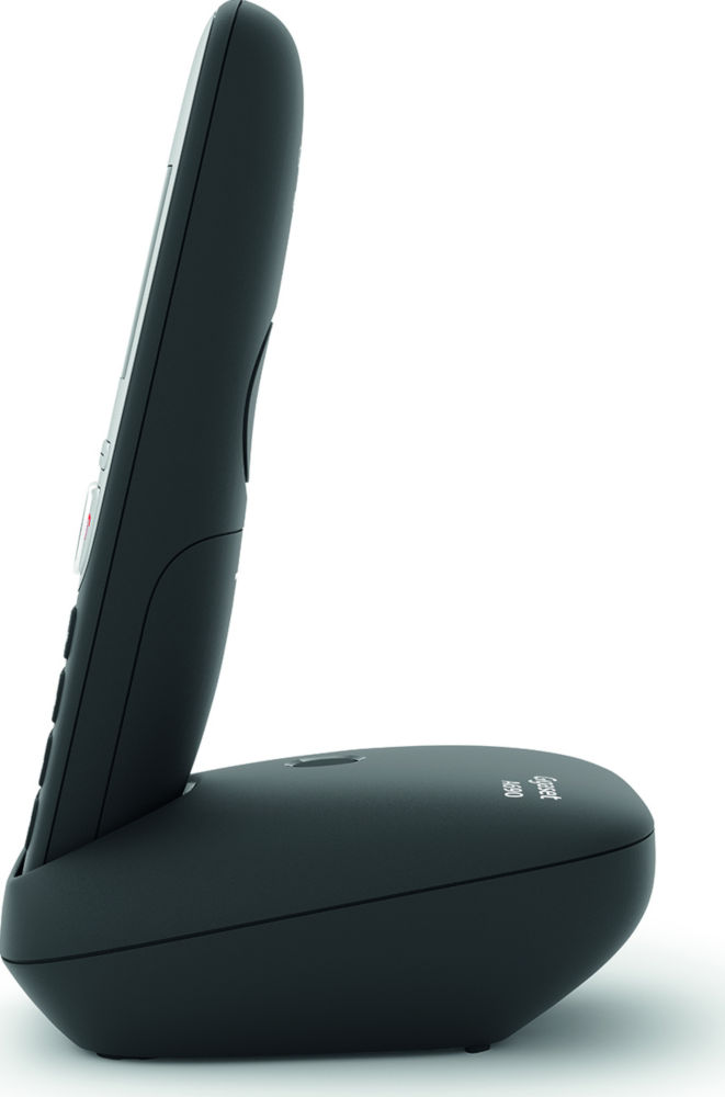 Téléphone sans fil noir sur une base noire, vu de côté. Il est sur une surface blanche.