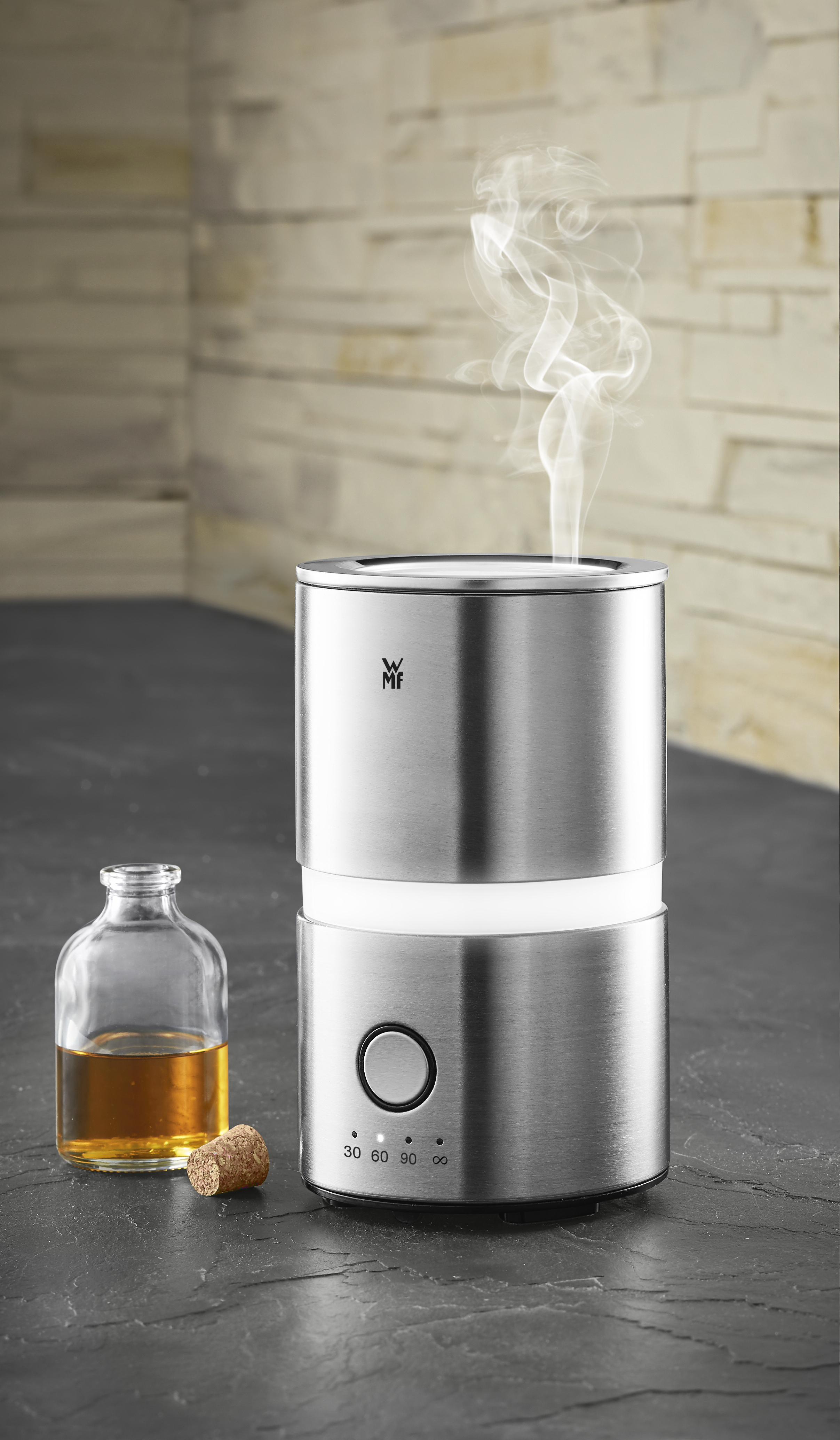 Silberner Diffusor mit einer Glasflasche mit Flüssigkeit und einem Korken. Rauch steigt aus dem Diffusor auf.