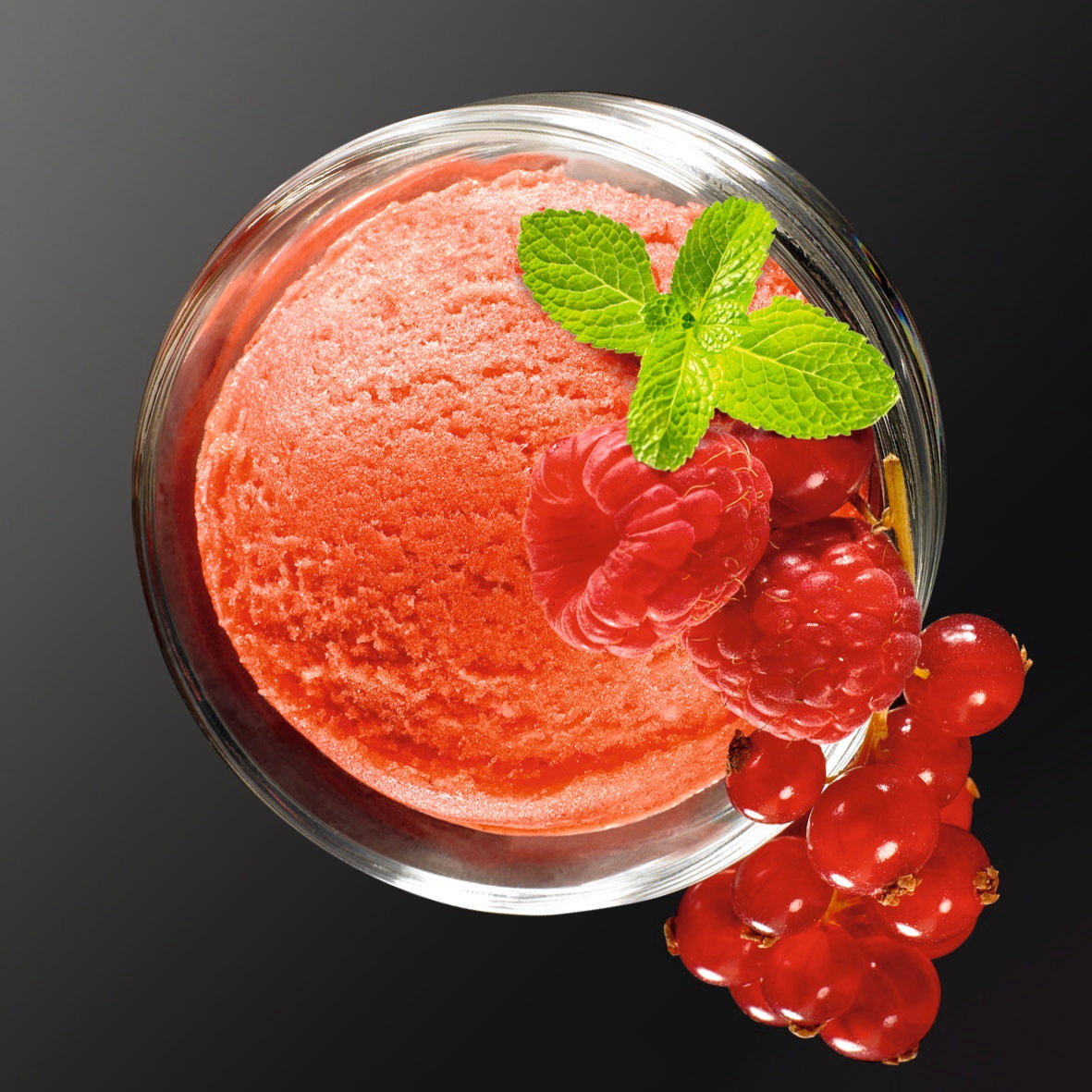 Kugel rotes Eis in einer Glasschale, Himbeeren, Johannisbeeren, Minz-Garnierung.