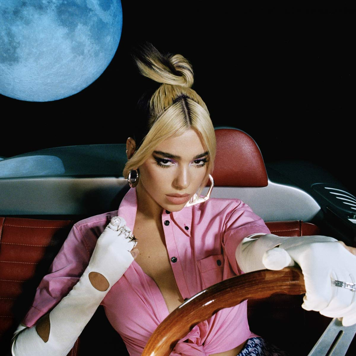 Dua Lipa egy régi autót vezet egy kék holddal.
