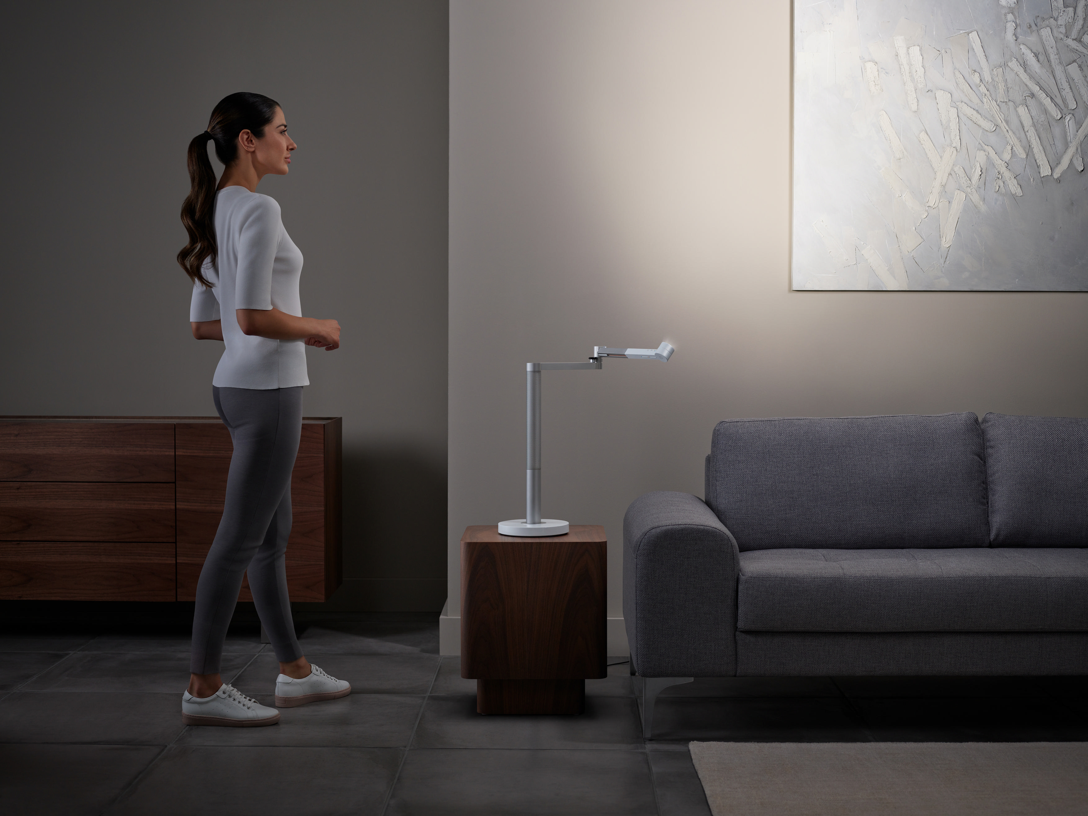 Eine Frau, die in der Nähe einer modernen Lampe und eines Sofas geht.