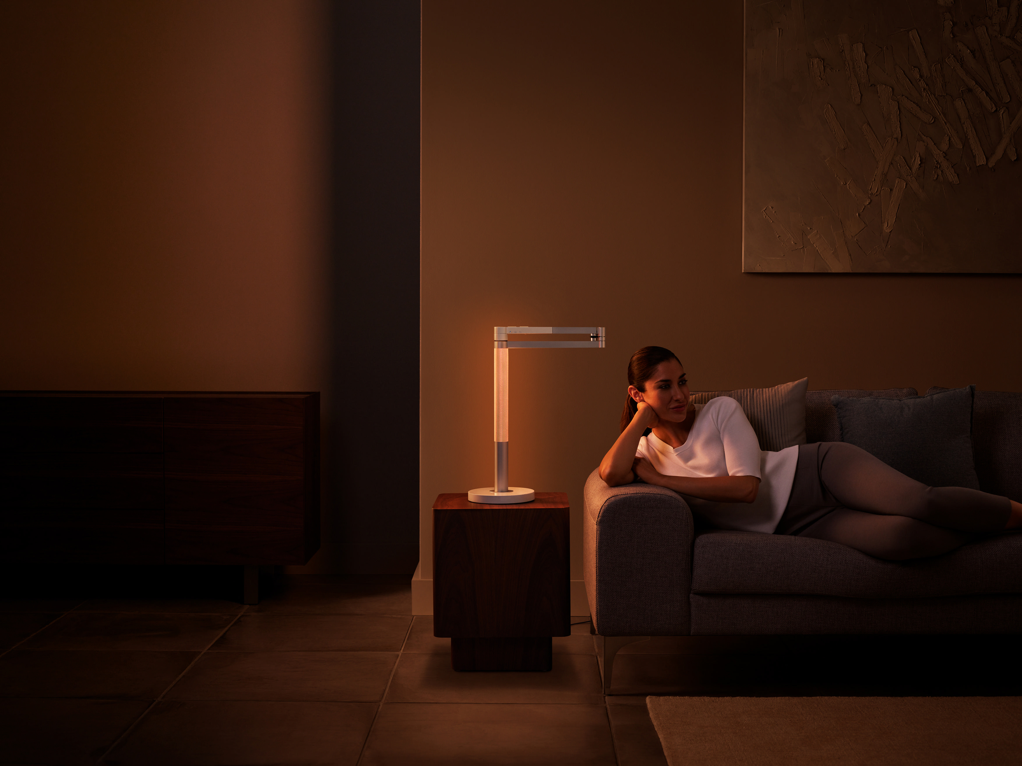 Eine Frau ruht auf einer Couch neben einer Lampe und einem Holztisch.