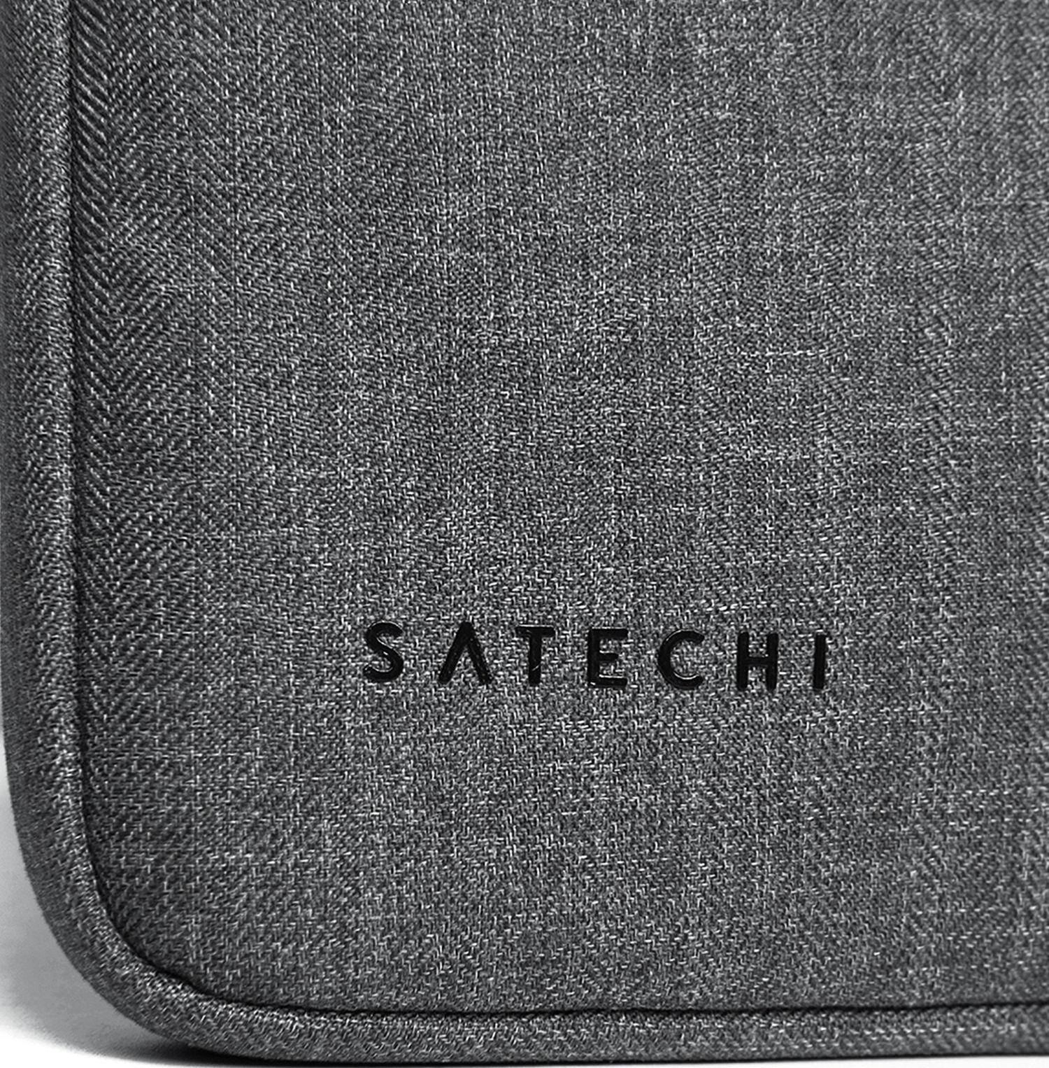 Primo piano su un tessuto grigio con il marchio 'SATECHI' stampato in nero.
