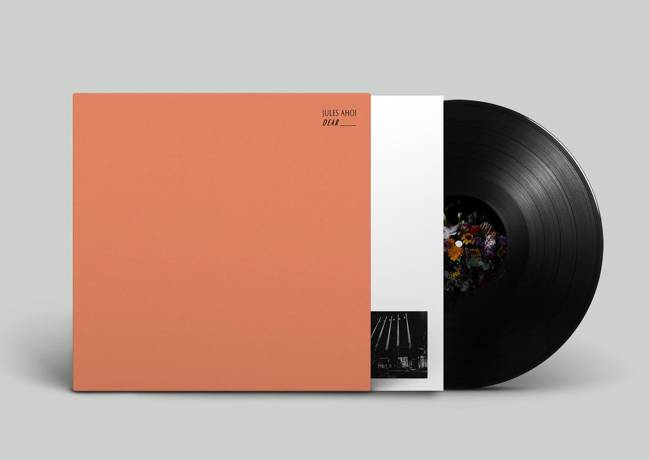 Ein Vinyl-Schallplatten-Albumcover. Es hat ein orangefarbenes Cover mit dem Albumtitel und eine schwarze Vinyl-Schallplatte.