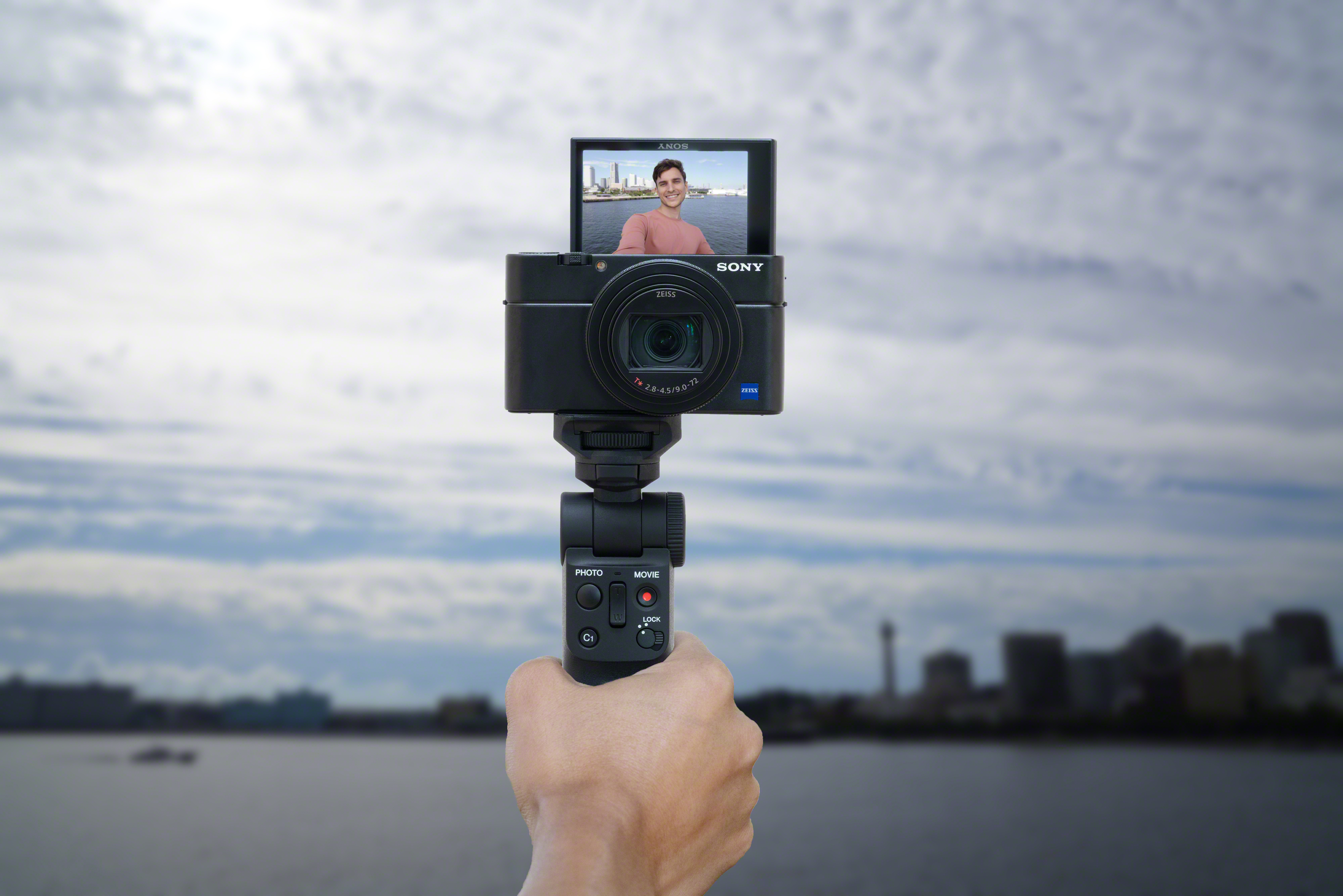 Een persoon gebruikt een camera met selfiescherm, stadsachtergrond.
