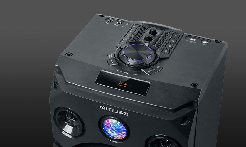 Egy fekete hangszóró a tetején egy vezérlőpanellel. A hangszórón Muse logó és színes diszkógömb látható.