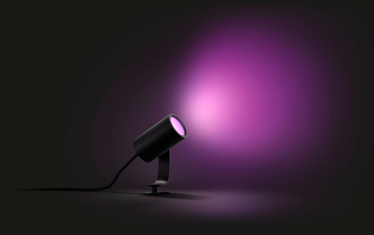 Un projecteur noir illumine un faisceau violet sur un fond sombre.