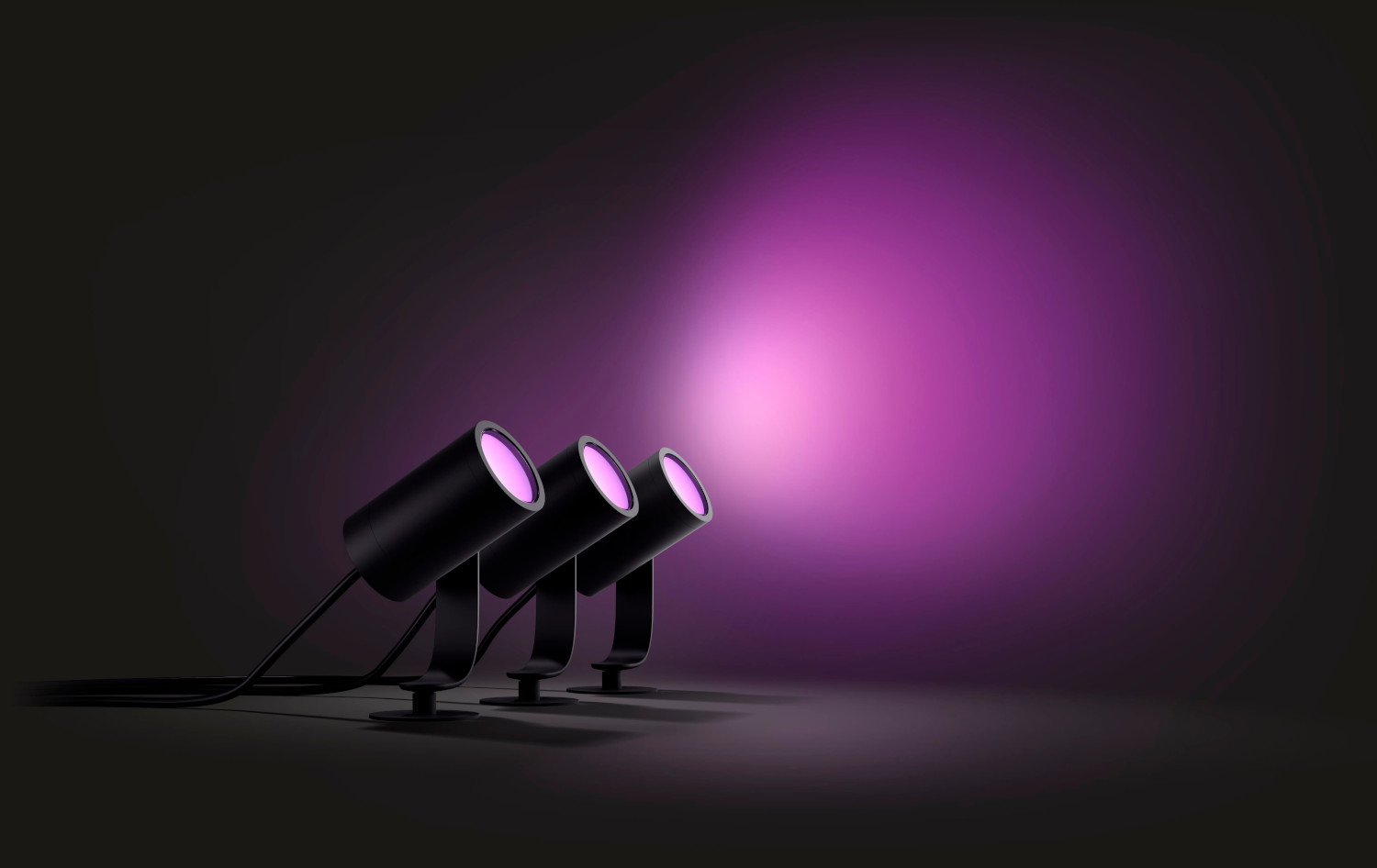 Three black Philips spotlights shining on a pink background.