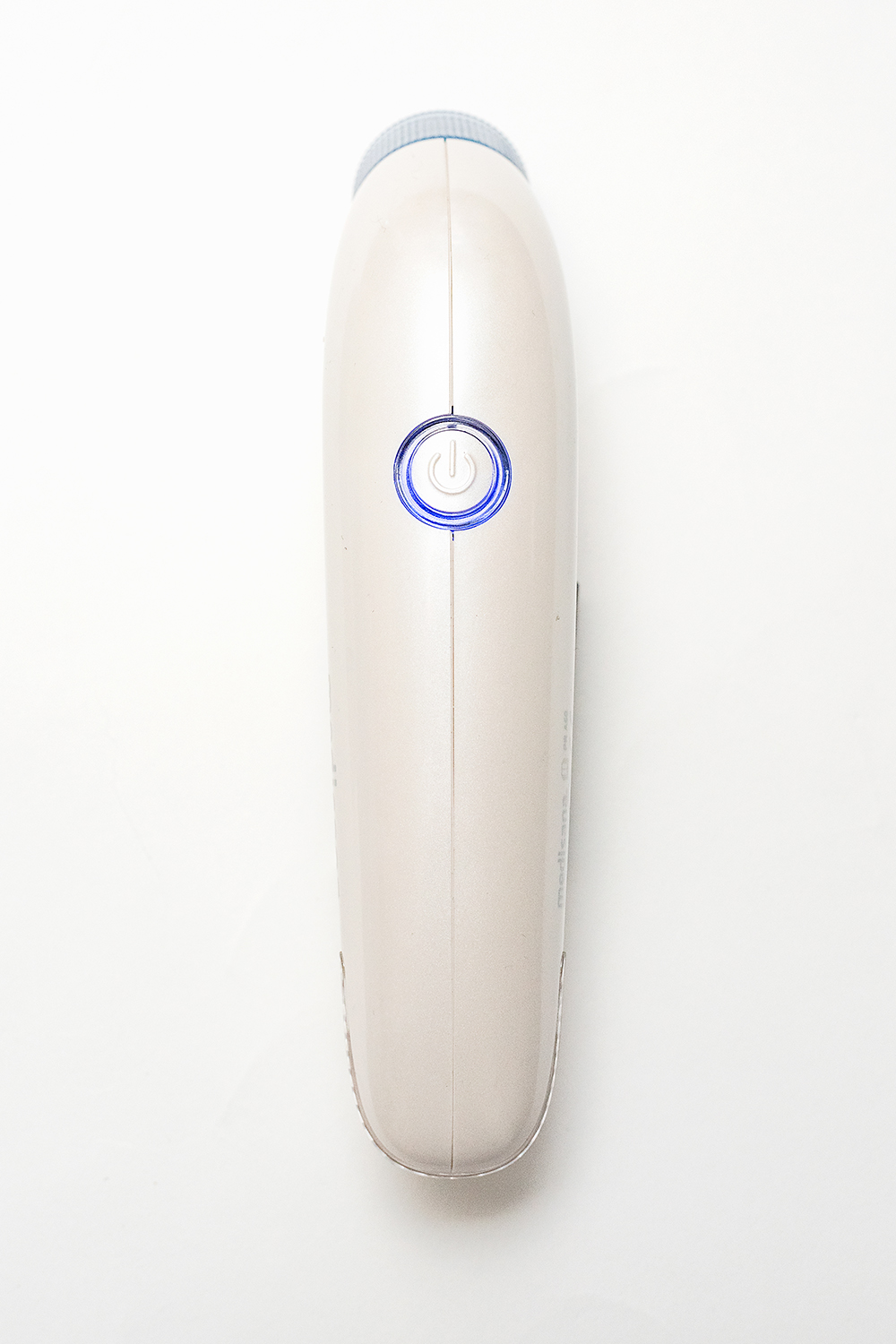 A beige electric shaver, top view, with a blue power button. Set against a white background.