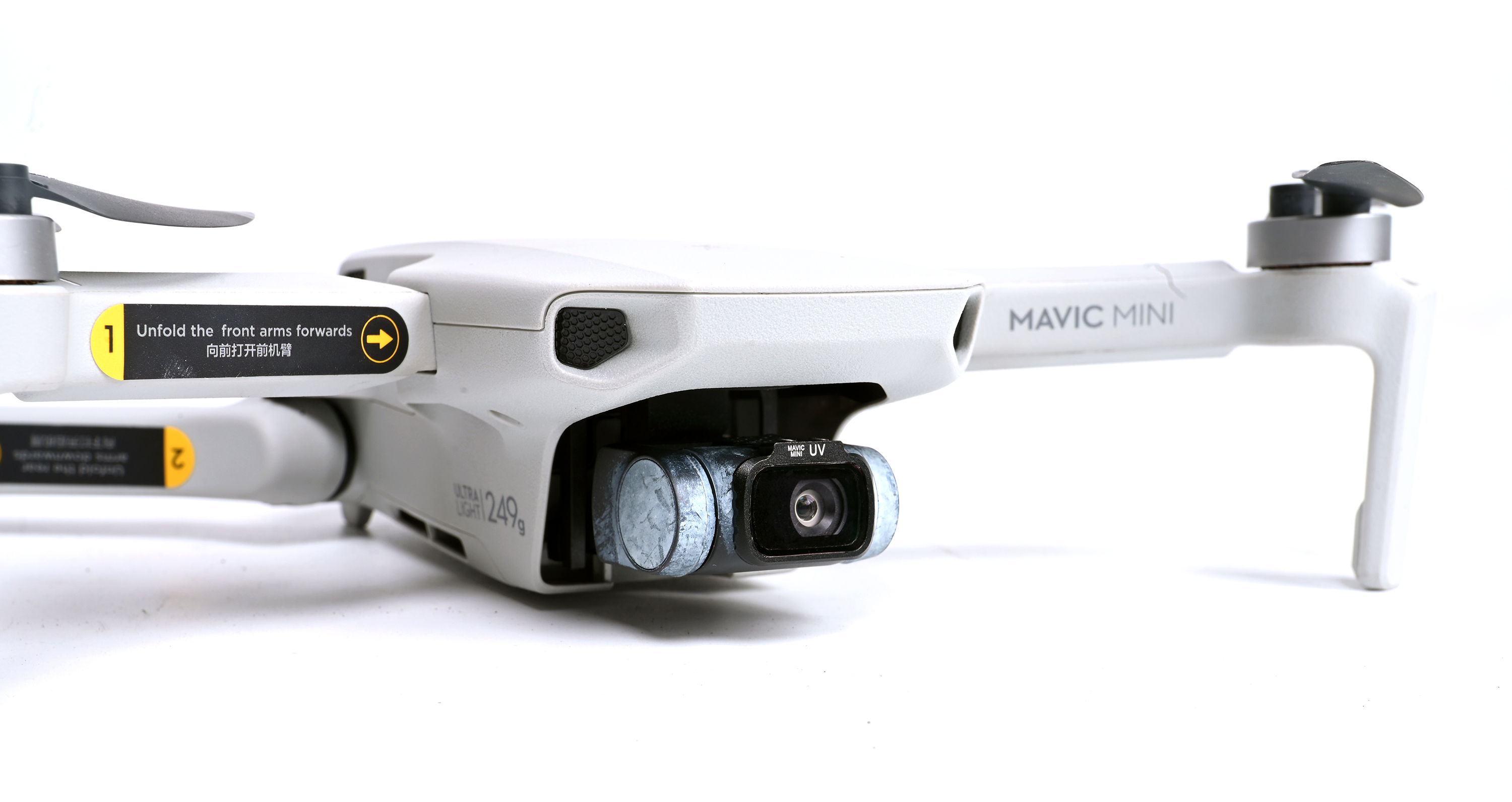 A drone with a camera. The drone is white and gray. The background is white.