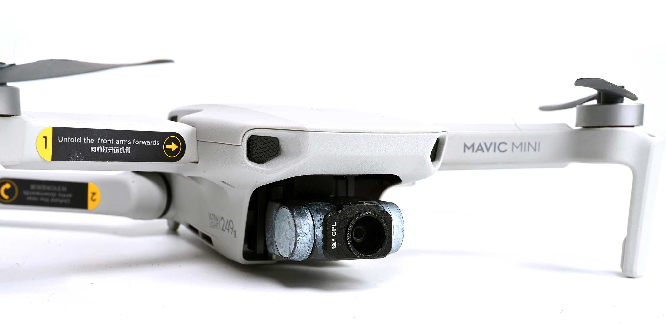 A drone with a camera. The drone is white and gray. The background is white.