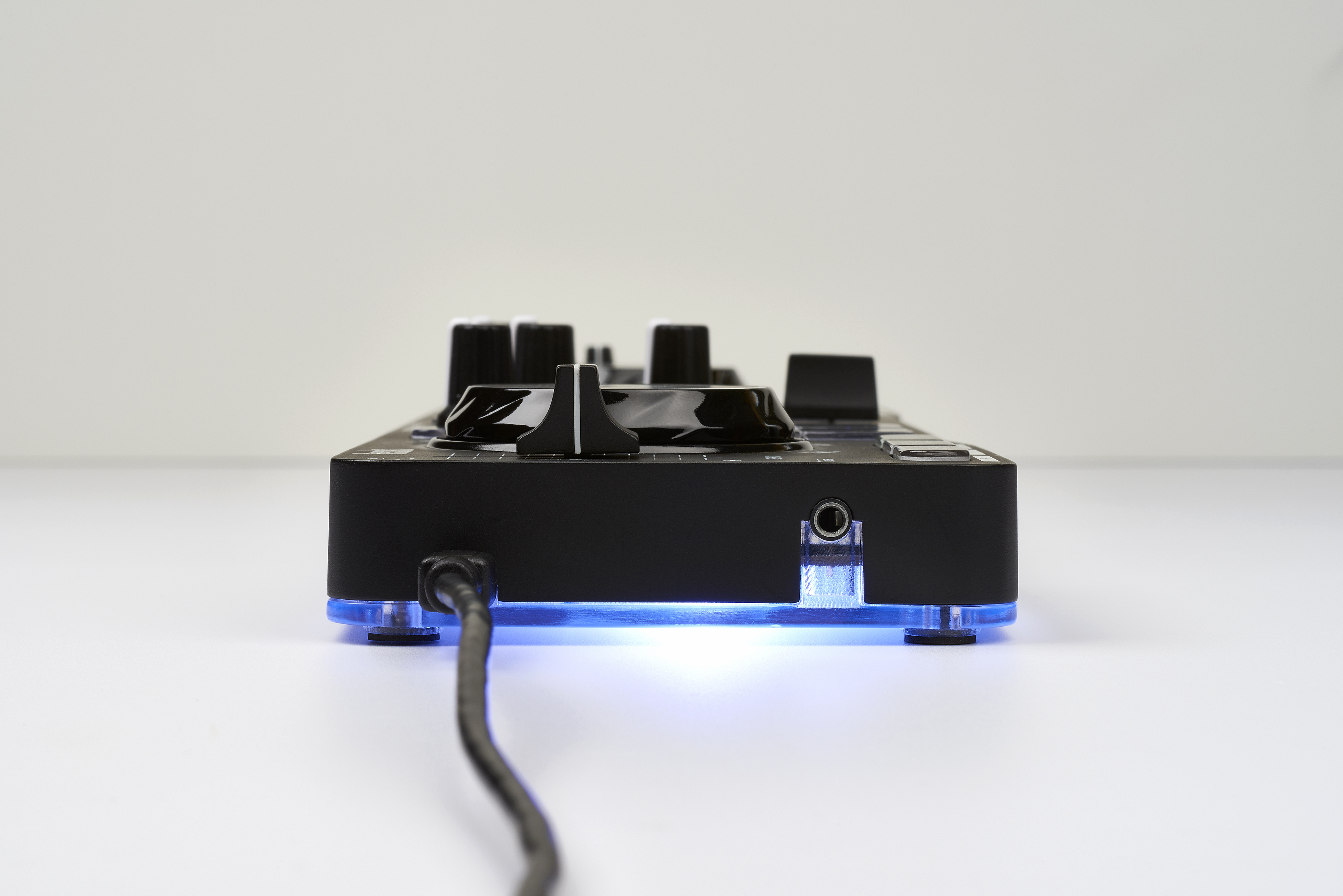 Schwarzer DJ-Mixer von der Seite, Knöpfe und eine blau leuchtende Basis.