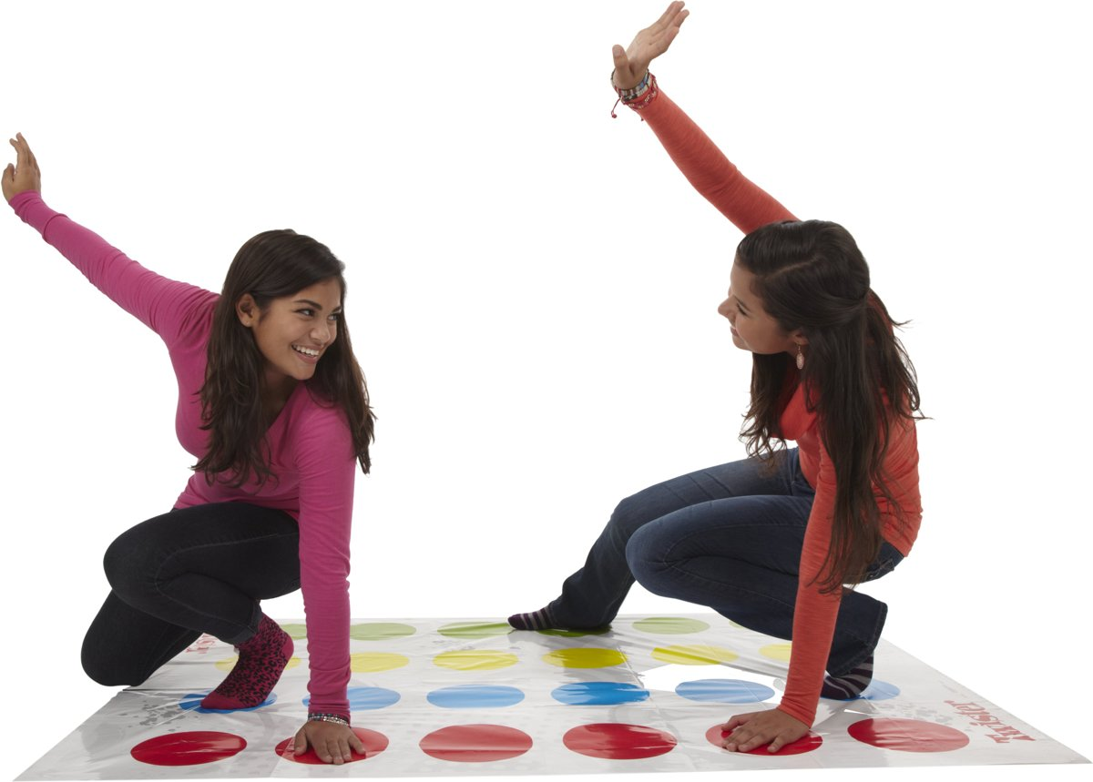 Deux filles jouent au Twister. Une en rose, une en rouge. Elles sont sur le tapis, bras levés, souriantes. Focus sur le jeu.