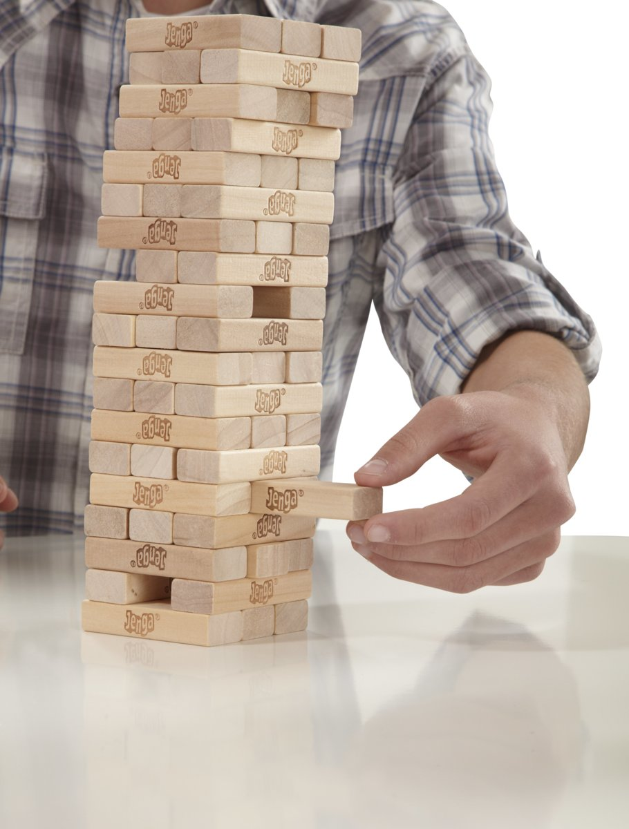 Person removing a Jenga block from a tower made of wooden blocks.