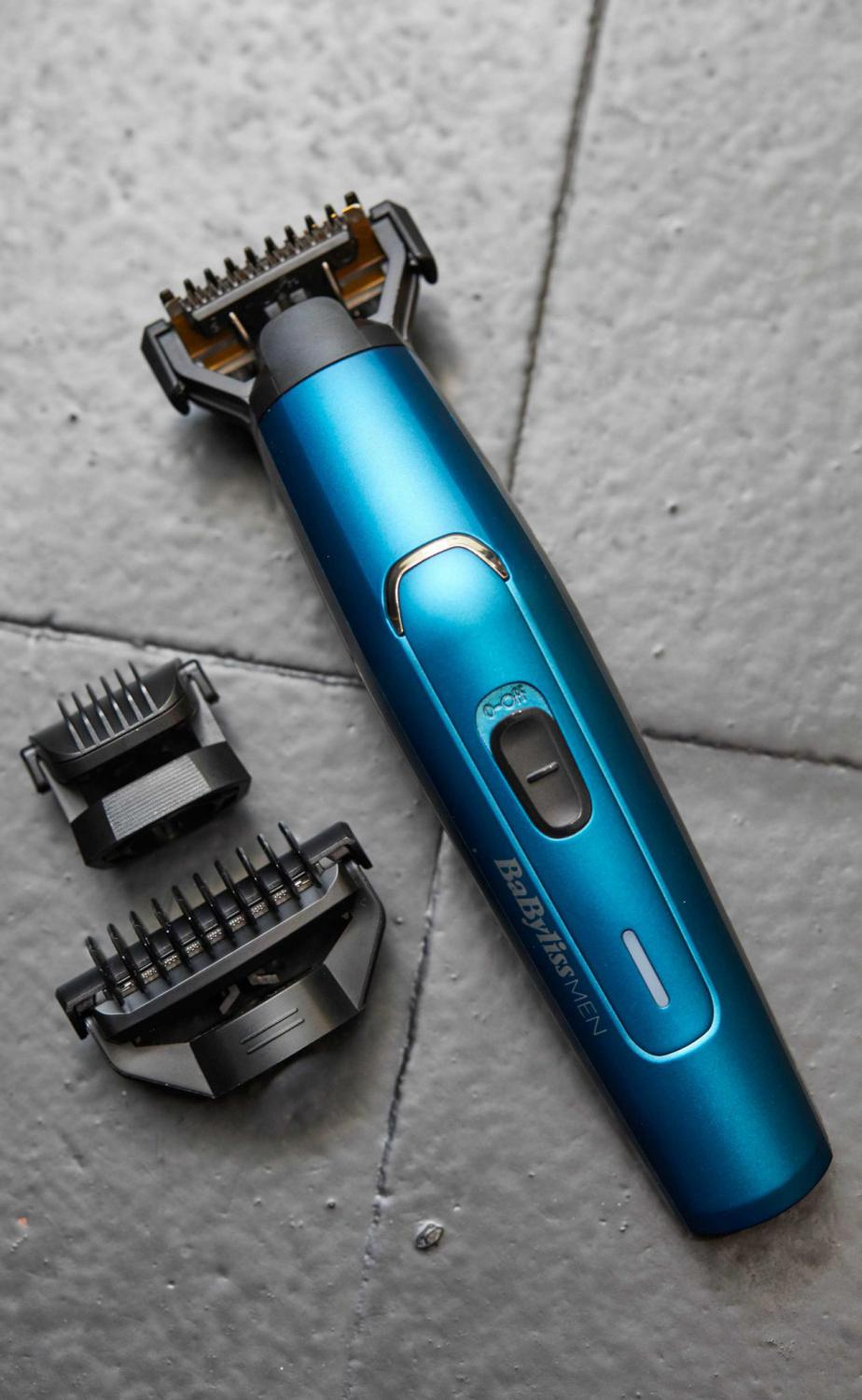 Trimmer per capelli blu con accessori. È posizionato su una superficie grigia.