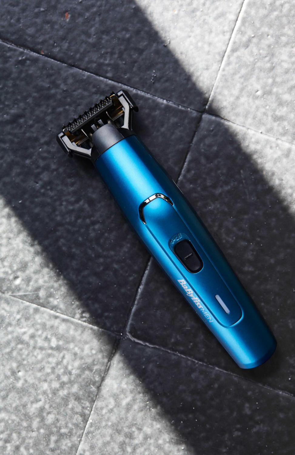 Rifinitore elettrico blu su una superficie piastrellata scura. Testina di taglio nera.