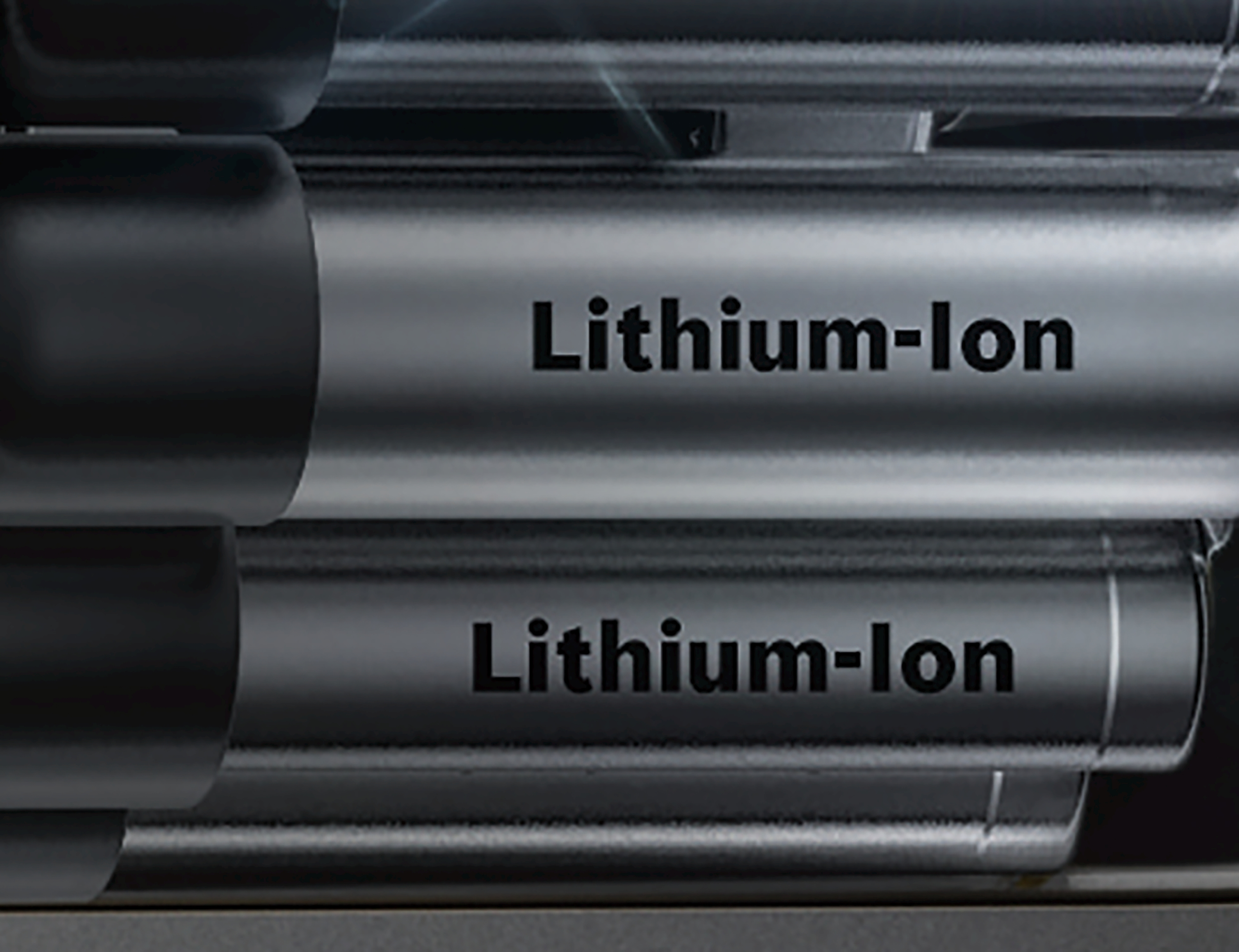 Nahaufnahme von Lithium-Ionen-Batterien, zylindrisch, mit schwarzen Enden und Text 'Lithium-Ion'. Grauer Hintergrund.