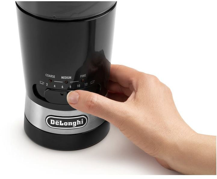 A black and silver De'Longhi coffee grinder with a hand pressing a button.