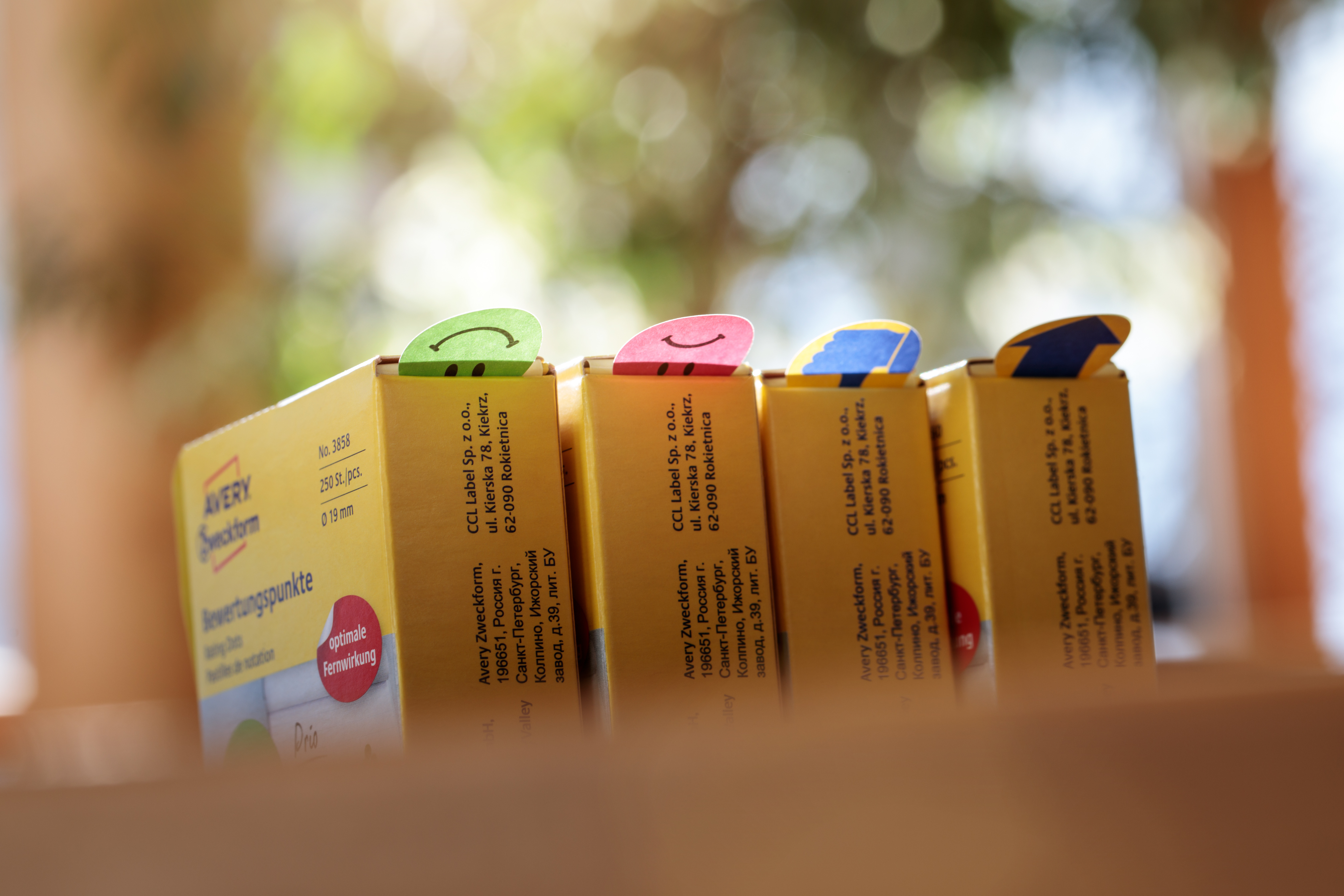 Nahaufnahme von gelben Boxen mit Smiley-Aufklebern. Der Hintergrund ist verschwommen und grün.