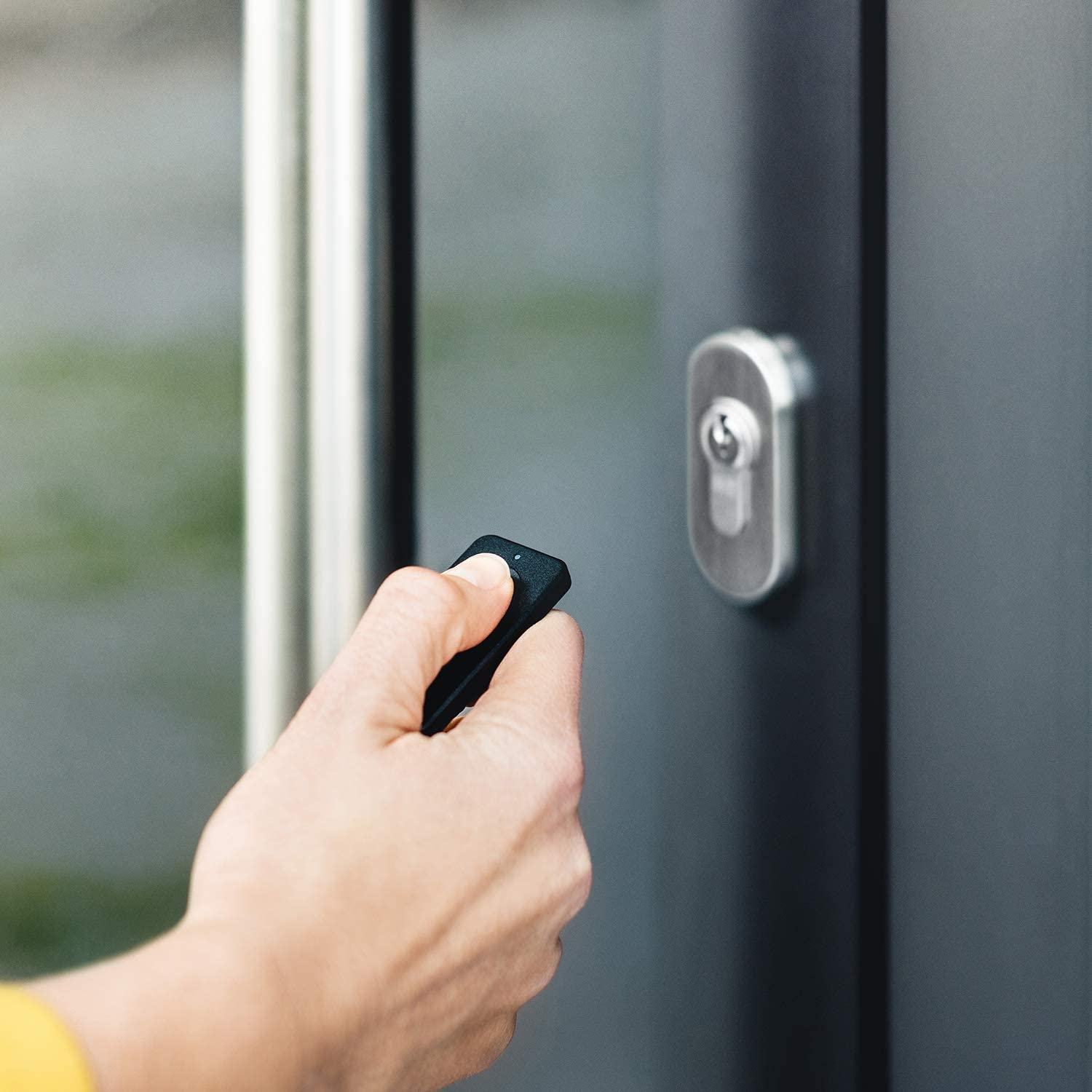 Una mano sosteniendo un mando a distancia negro cerca de una puerta.
