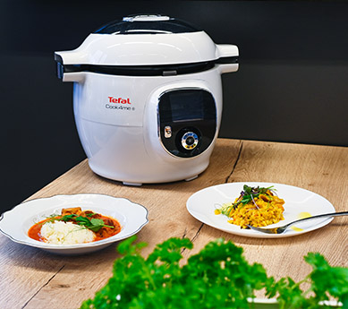 Egy fehér-fekete Tefal Cook4me+ készülék ételekkel faasztalon.