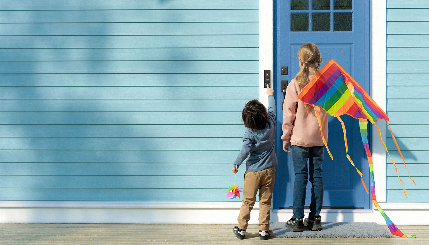 Twee kinderen bij een lichtblauwe deur met een kleurrijke vlieger.