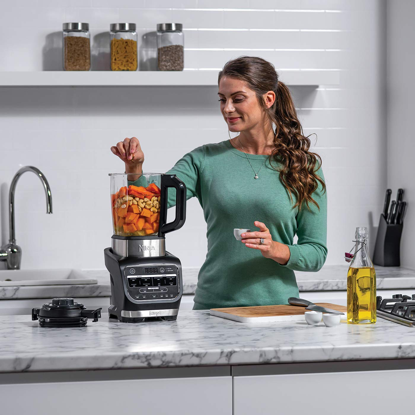 Femme utilisant un robot culinaire Ninja dans une cuisine.
