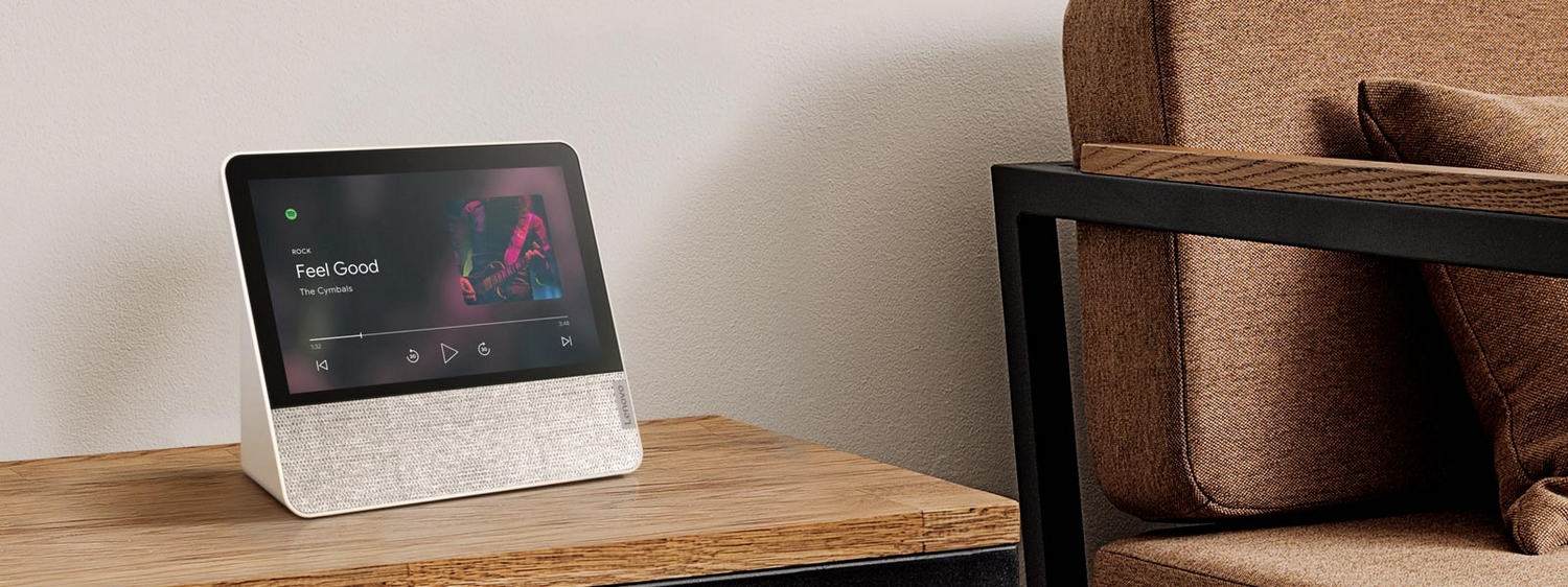 Dispositivo para el hogar inteligente sobre una mesa de madera. Muestra información musical con base de altavoz de tela.