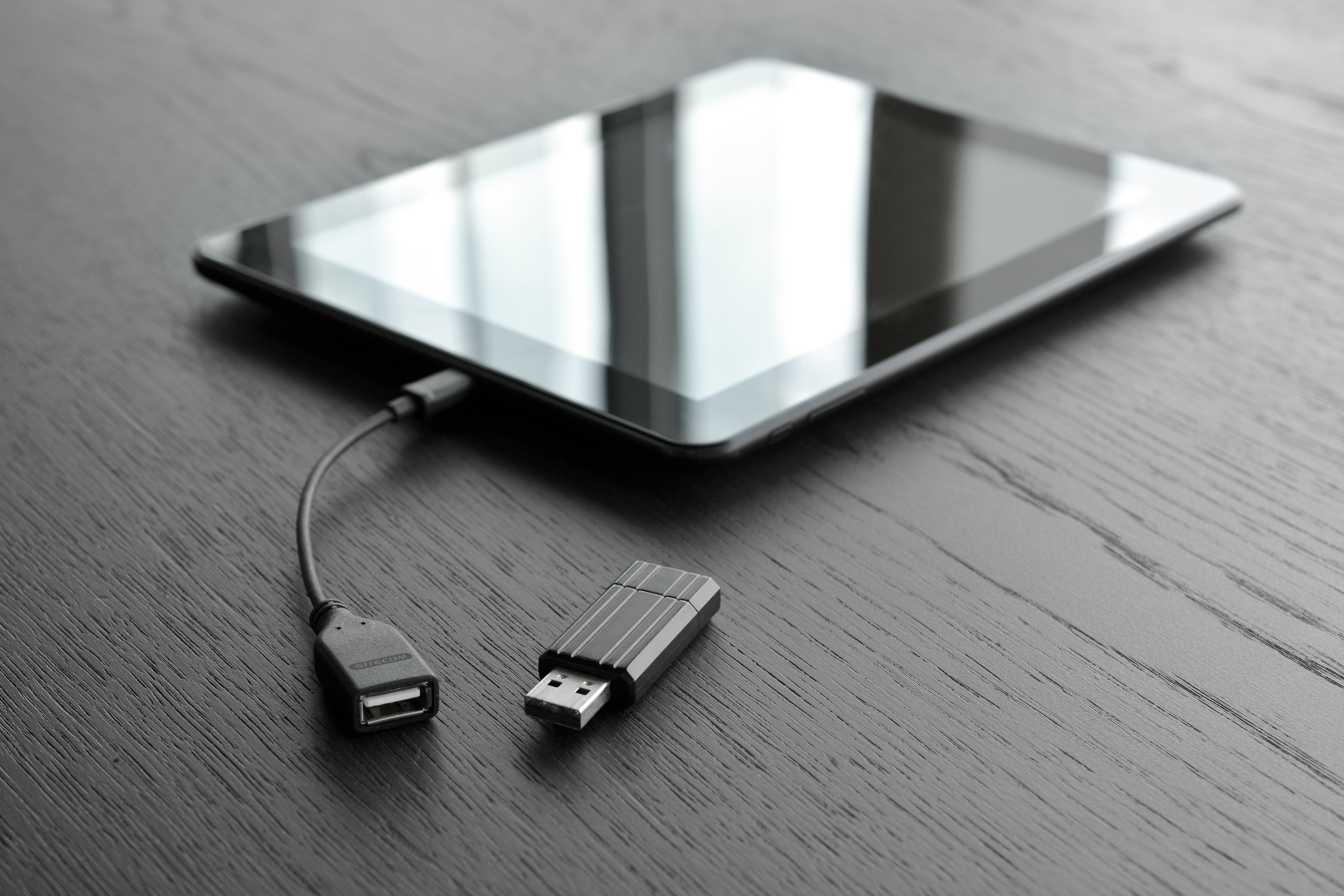 A tablet connected to a USB adapter. The adapter is plugged into a USB port.