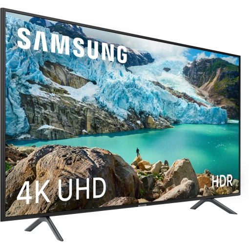 Un televisor Samsung mostrando una escena de la naturaleza. Montañas con agua y una persona en una roca.
