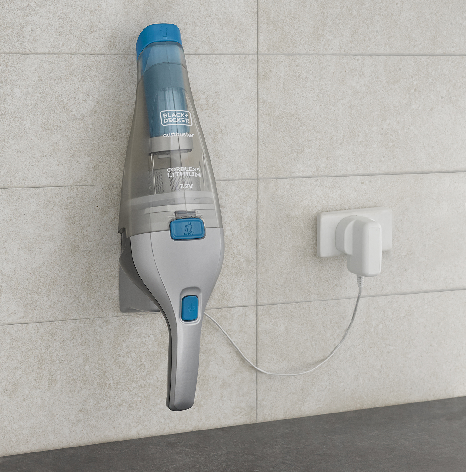 Gray and blue hand vacuum cleaner, plugged into a wall outlet.