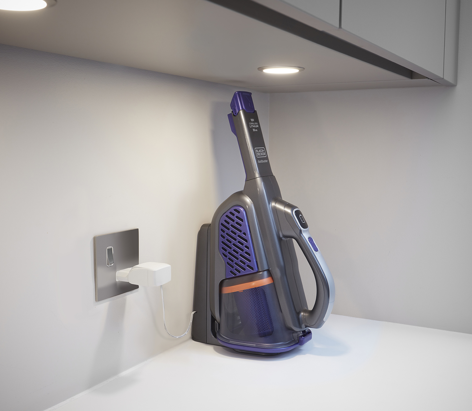 Een draadloze stofzuiger die oplaadt op een wit oppervlak naast een stopcontact.