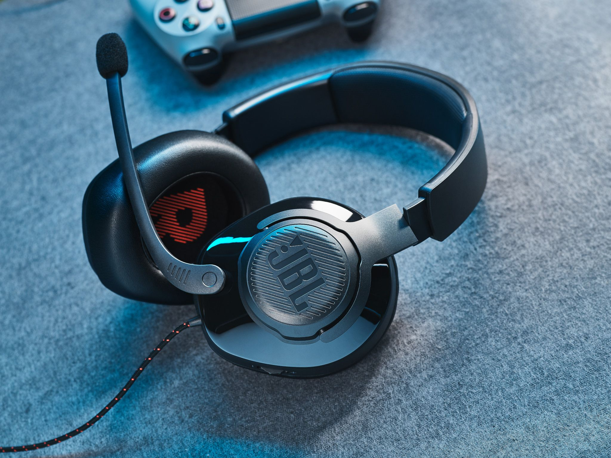 Zwarte JBL gaming headset met een microfoon. Controller op de achtergrond.