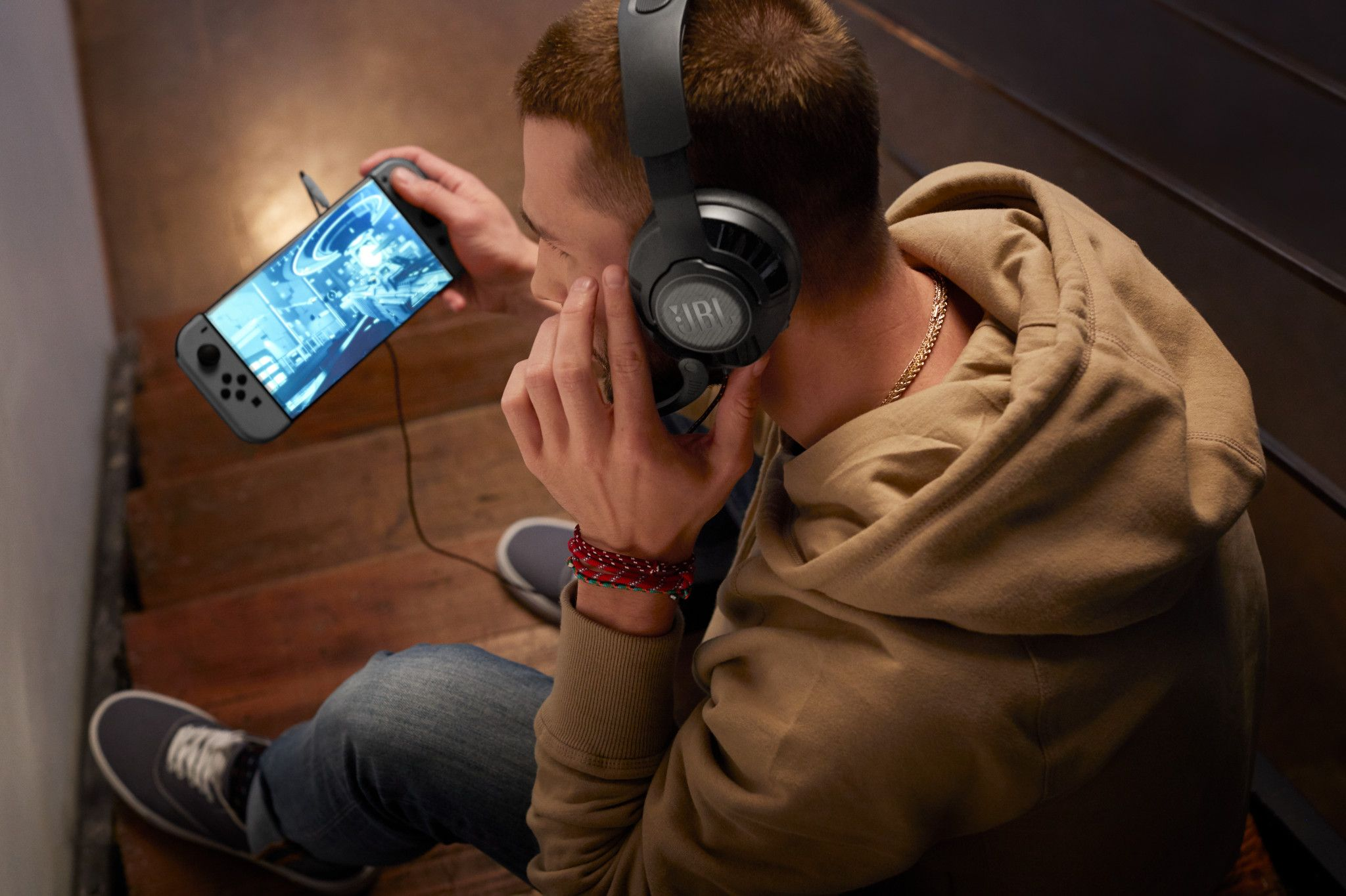Man met een JBL-koptelefoon, die een spel speelt op een handheld console.