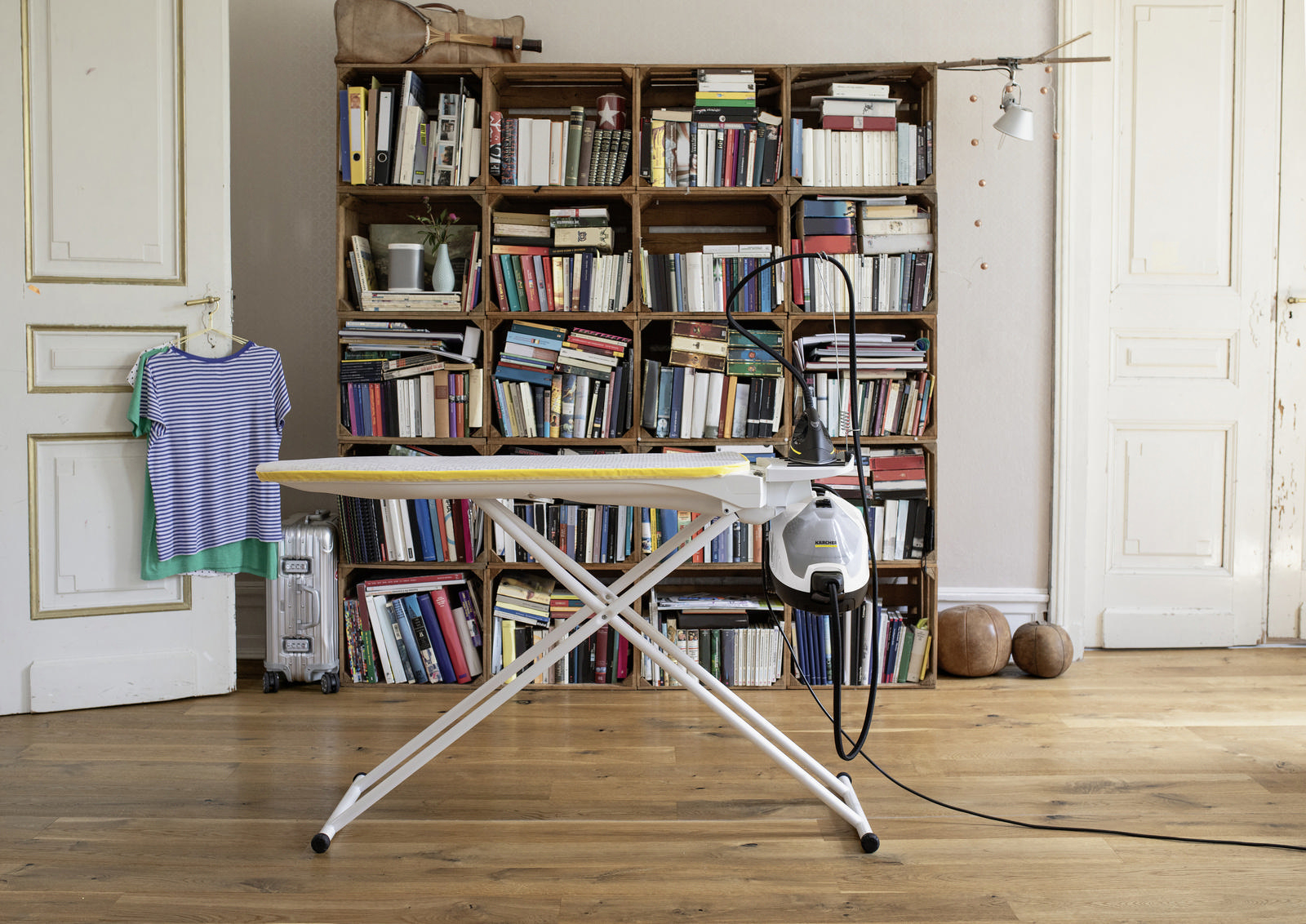 Ein Bügelbrett, das in einem Raum mit Büchern und Kunst aufgestellt wurde.
