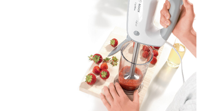 Persoon aardbeien aan het mixen met een Bosch staafmixer.